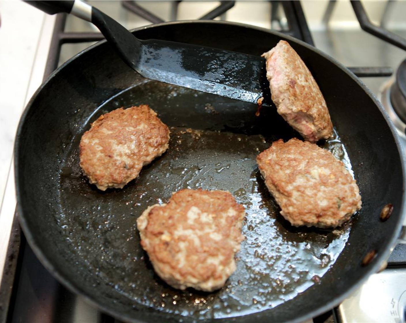step 8 Heat a large saute pan, or griddle, to medium-high heat. Add Vegetable Oil (1 Tbsp). When the oil shimmers and wisps slight traces of smoke, add the burgers.  Place the bottom edge in the oil, and allow the top edge to fall away from you.