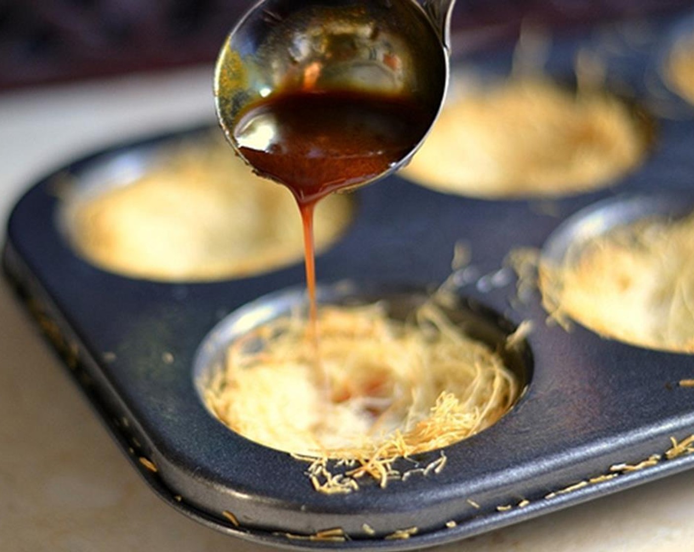 step 11 To assemble the apple pie kunafas, remove the baked kunafas and let cool. Drizzle each cup with caramel and set aside for five minutes.