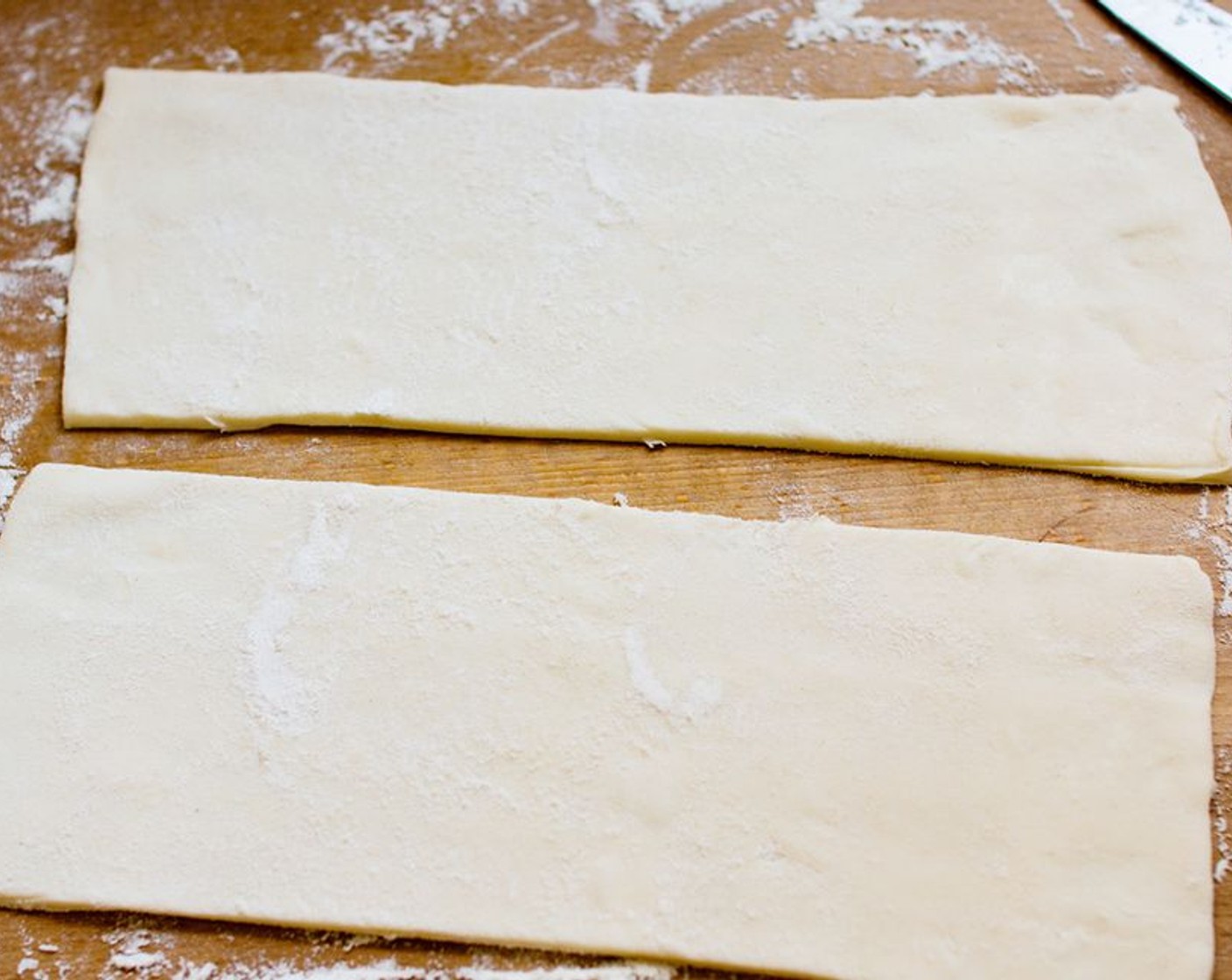 step 2 Sprinkle your worktop with a pinch of All-Purpose Flour (1 pinch), lay out your Puff Pastry (1 sheet) gently and halve it lengthwise, so you have two long and thin rectangles.