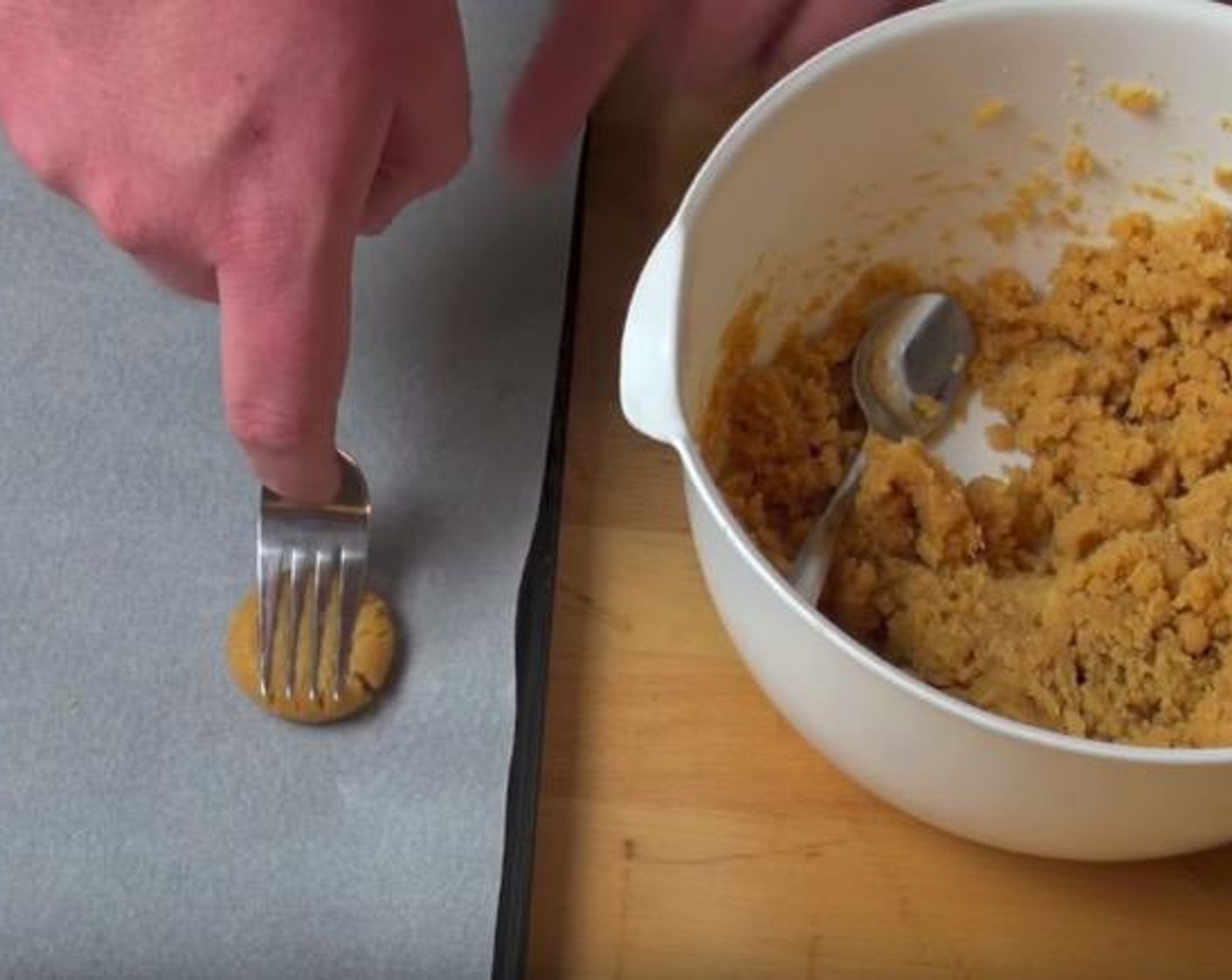 step 2 Take a teaspoonful of cookie dough mixture and roll it in your hand to make a little ball. Put the ball on a baking tray lined with some non-stick baking paper. Use a fork to gently press down the ball. Finish the rest in this way.