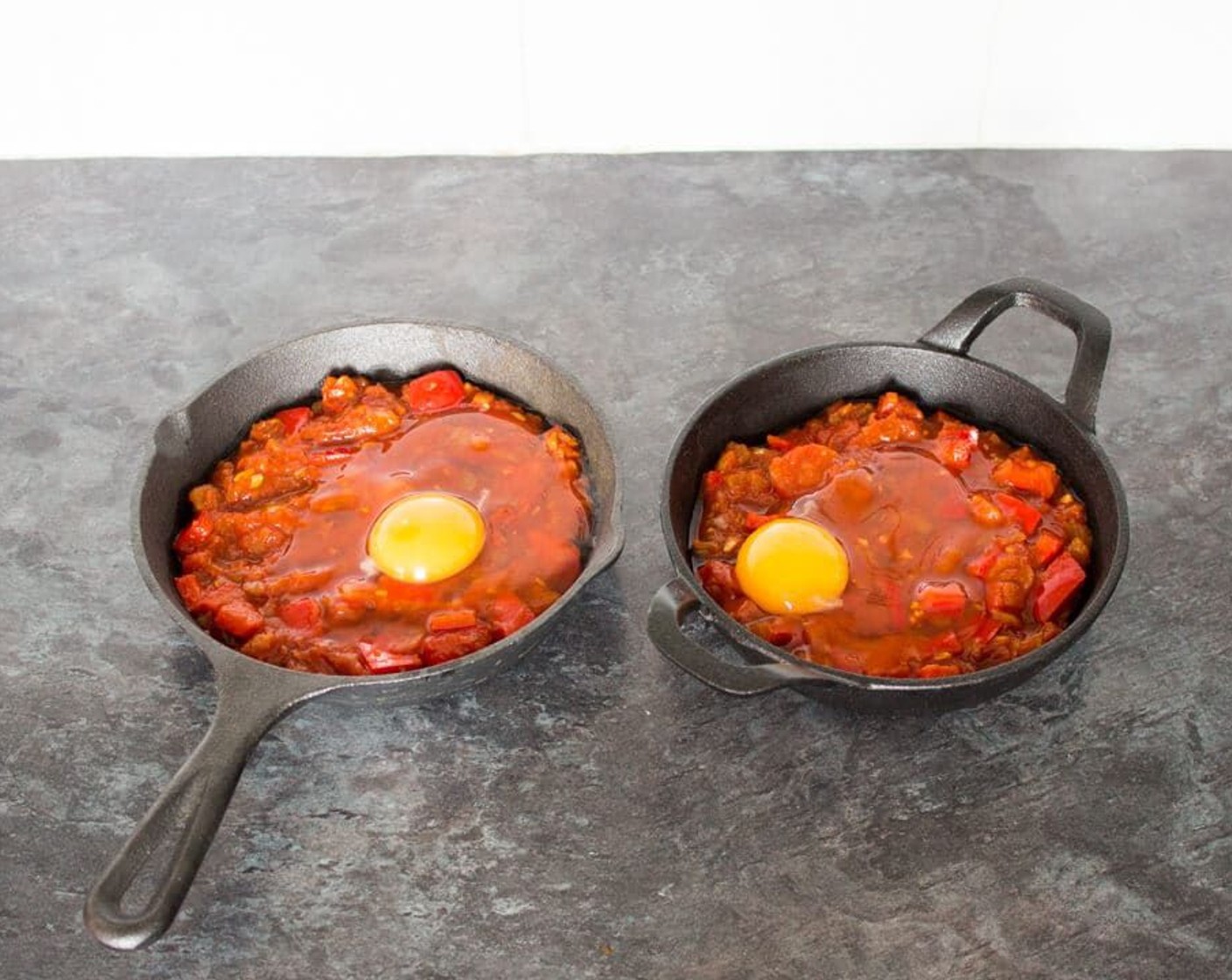 step 6 Then you can do one of two things. Either leave the tomatoes in your oven proof pan and crack over Eggland's Best Classic White Eggs (2) or you can split it between two oven proof dishes or small cast iron pans and crack an egg into each one.