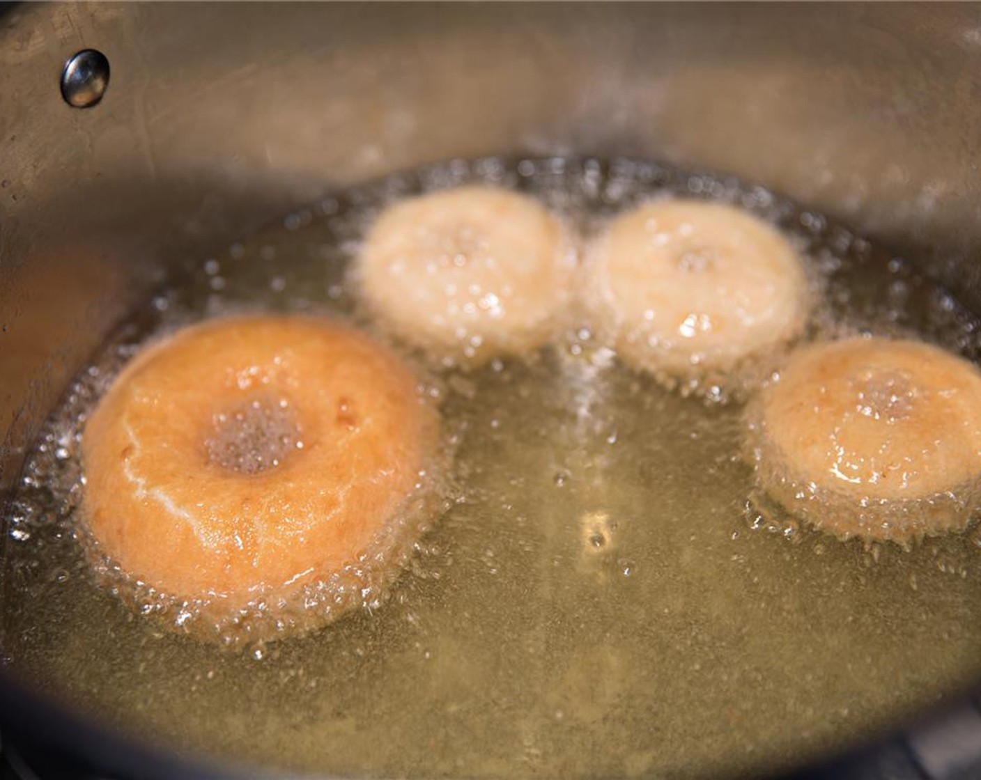 step 7 Pour Sunflower Oil (as needed) into a deep frying pan until 1 1/2 inches (4 centimeters) deep. On medium-high, bring oil to 330 degrees F (165 degrees C), and then turn the heat down to medium-low. Gently place a few doughnuts into the oil, ensuring they don't stick together.