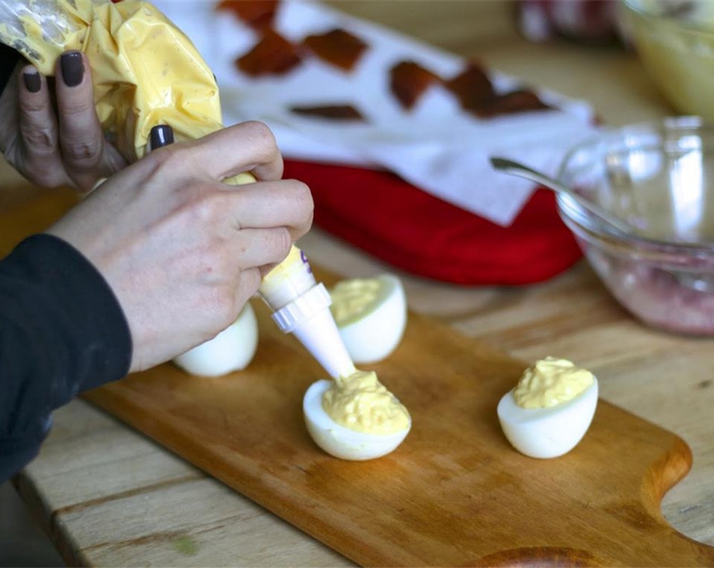 step 13 Cut the end off the piping bag or freezer bag and fill egg cups evenly until all the yolk mixture is used. Top each egg with a slice of pickled jalapeno. Break the crispy bacon into pieces and top the egg.