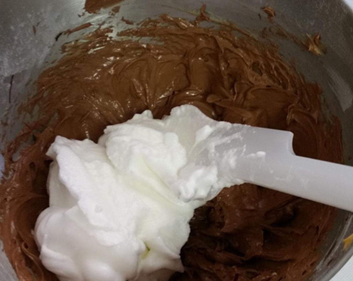 step 7 Vigorously stir about 1/3 of the whipped egg whites into the chocolate mixture to lighten it, then gently fold the remaining egg whites into the chocolate mixture with a spatula until just a few wisps of egg white remain. Do this carefully so as not to deflate the egg whites.