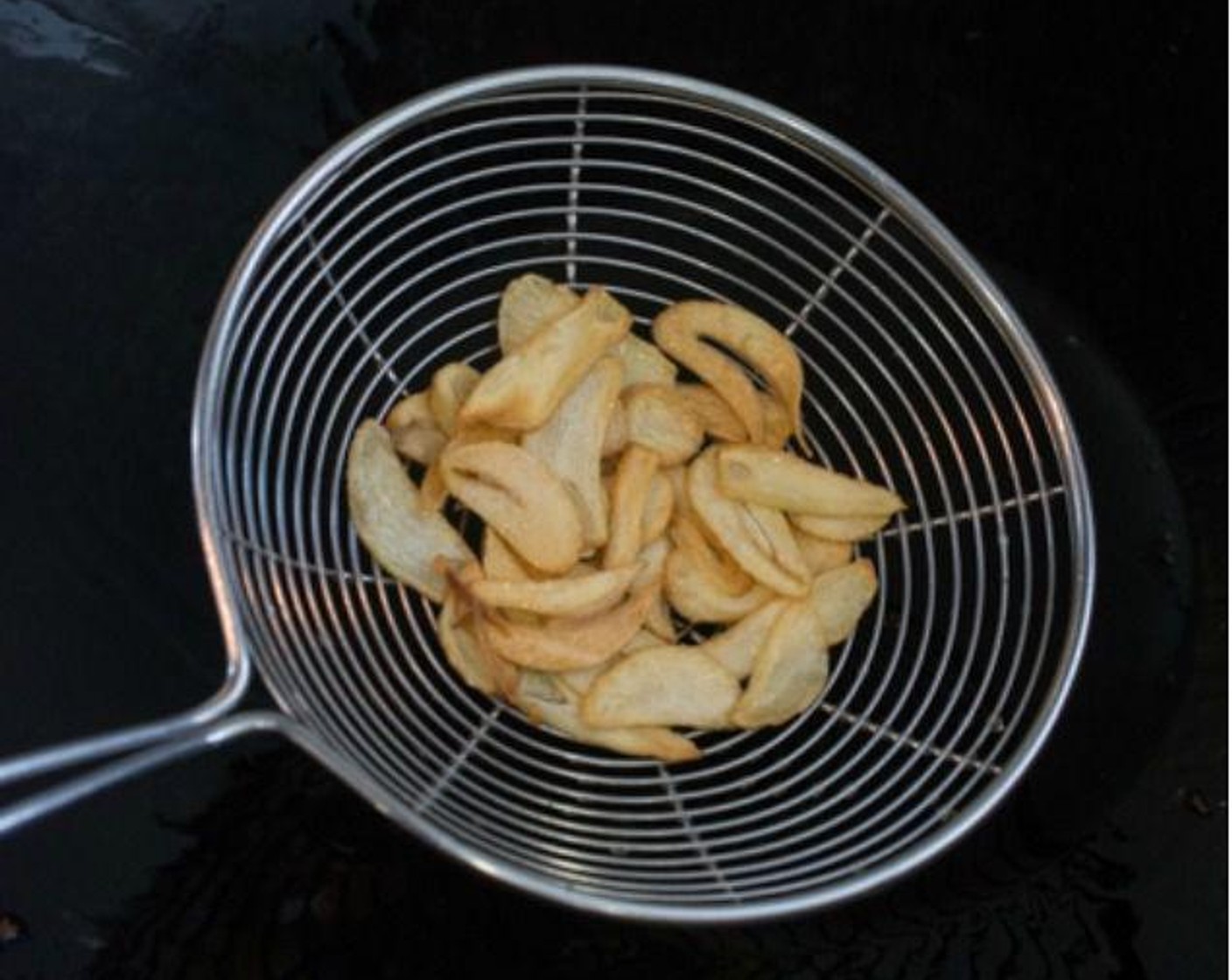 step 2 Pour Olive Oil (1/2 cup) into a wok and add the Garlic (3 cloves) into the cold oil. Turn on the heat to medium-high. As soon as the garlic slices start to sizzle, stir them constantly with a wok spatula to prevent them from sticking, and to ensure they cook evenly. When the garlic chips turn a very light golden brown, remove them from the wok with a fine mesh strainer or spider.