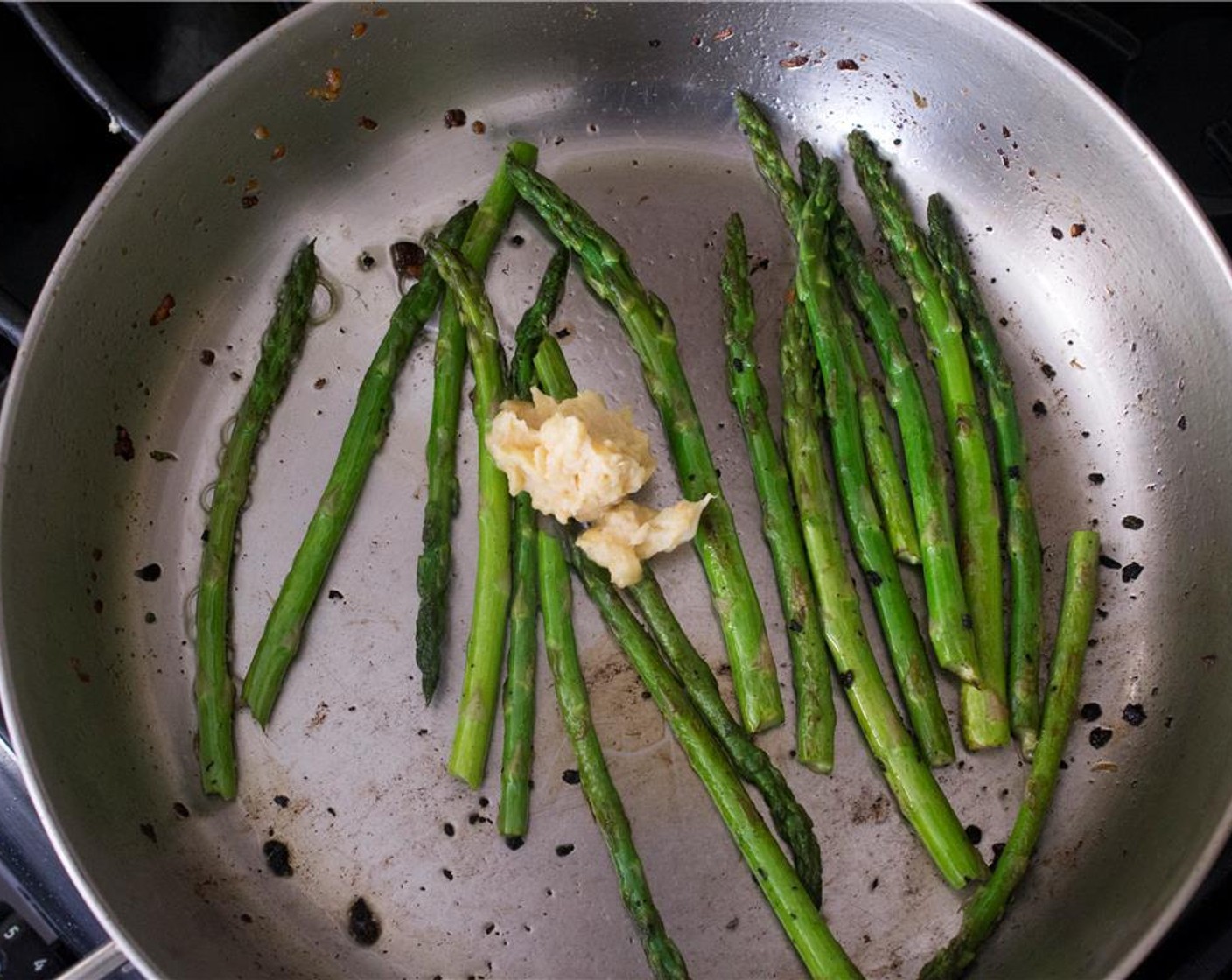 step 7 In a large skillet over medium-high heat, heat 1 tbsp of olive oil.  Add asparagus to the skillet. Cook for 2 minutes, turning occasionally.  Add 1 tbsp of the roasted garlic miso butter. cook the asparagus for another minute, until tender.