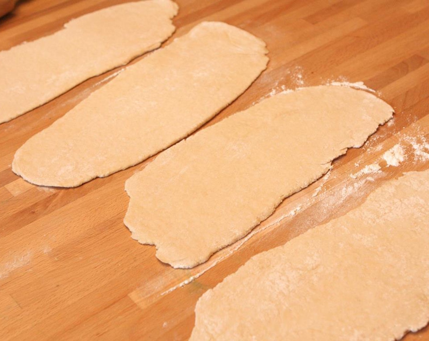 step 4 Turn out the dough onto a lightly floured surface. Divide into 4 equal pieces. Lightly dust hands and rolling pin with flour. Roll one of the four sections into a 12-by-4-inch rectangle.