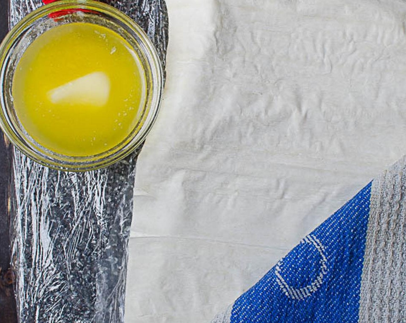 step 7 Cover your work surface in plastic wrap (this is optional, but it makes cleanup a lot easier). Place one sheet of Phyllo Dough (15 sheets) on the work surface. Use a pastry brush to spread melted butter along one half (lengthwise) of the phyllo dough.