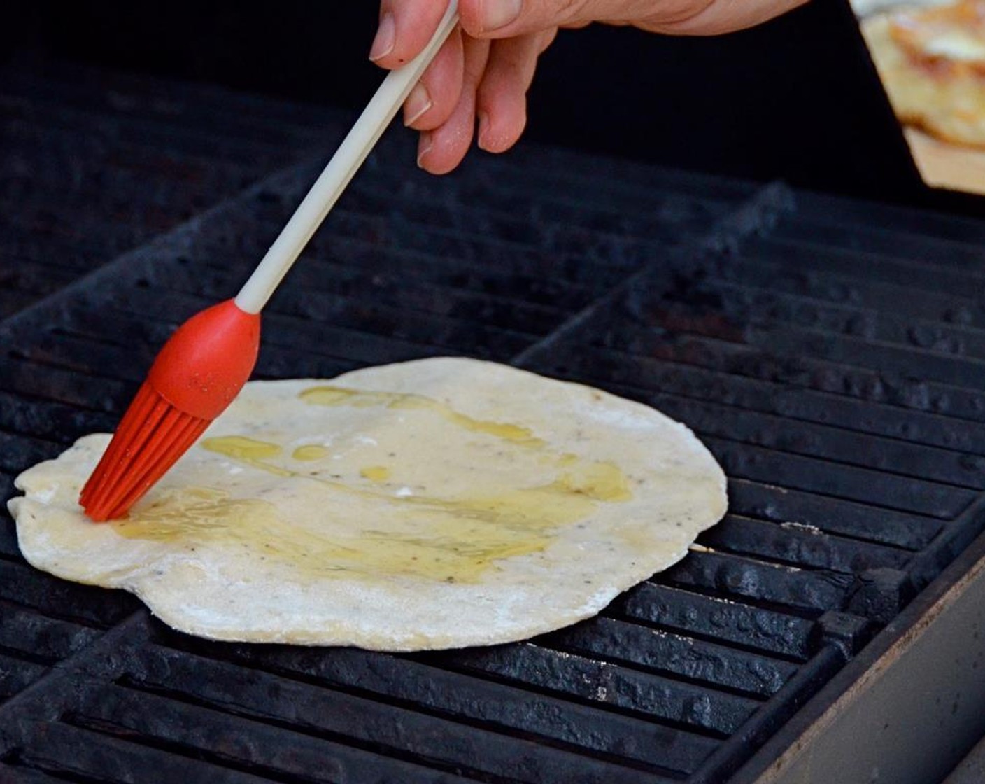 step 16 Place a pizza dough on the grill. Sprinkle with 1 teaspoon of olive oil and quickly brush the oil over the dough with a pastry brush.