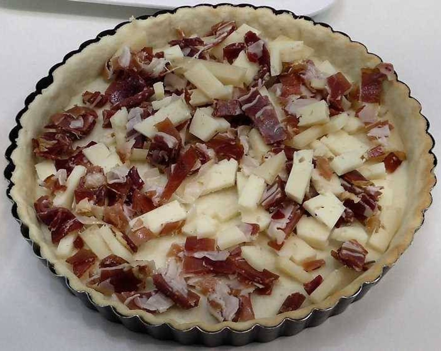 step 4 Remove the pie crust from the oven and remove the weights and paper. Fill the pie with Manchego Cheese (to taste) and Serrano Ham (to taste).