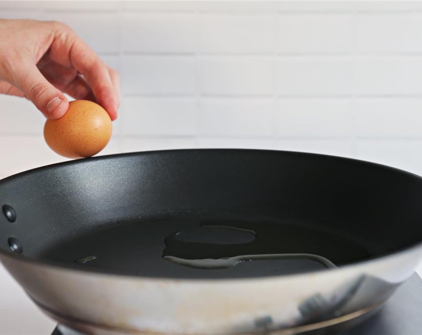 step 2 Once the oil is hot but not sizzling, gently crack the Eggland's Best Classic Egg (1) into the pan.