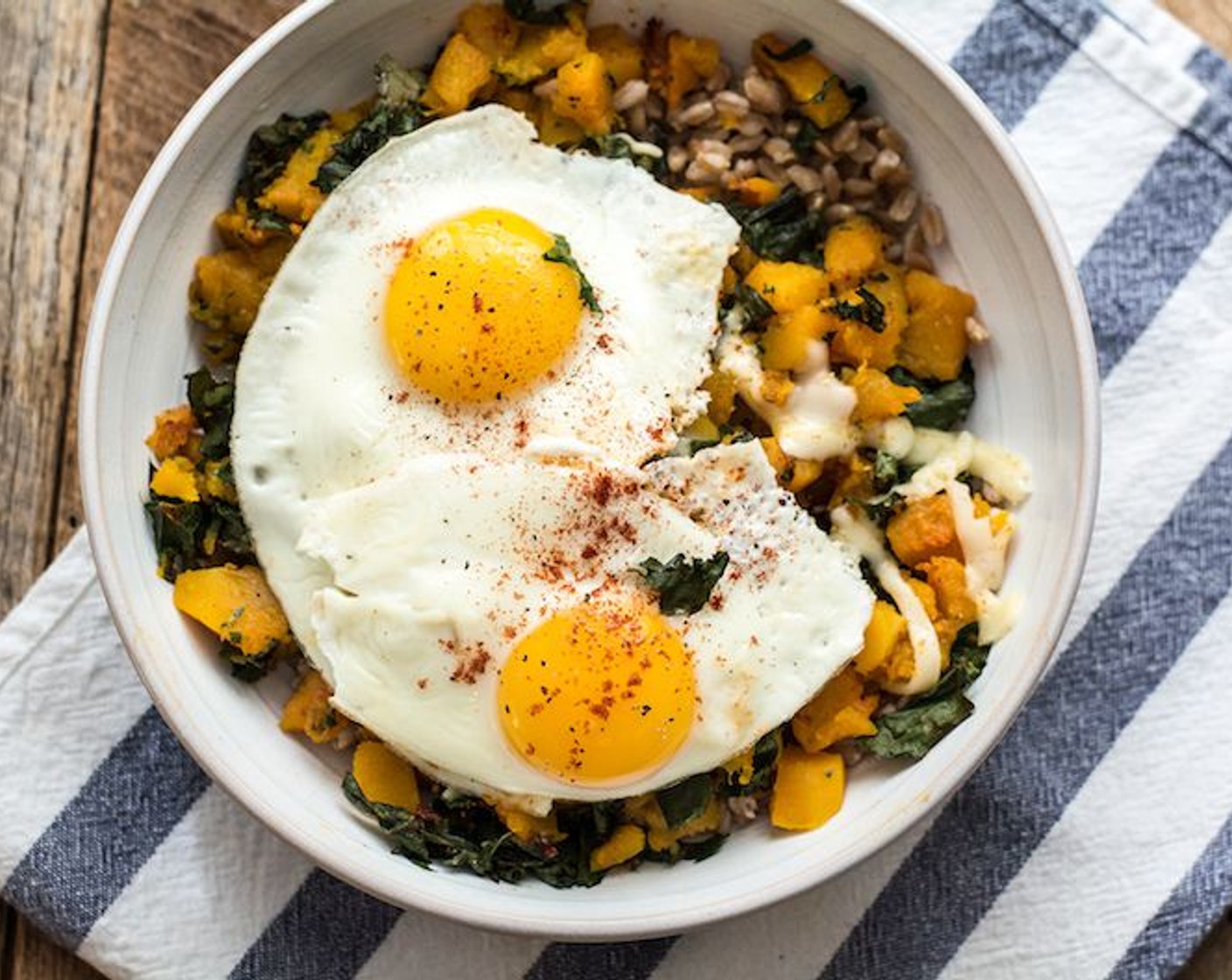 step 8 To assemble the bowls, add a layer of Farro, followed by half of the cooked veggies, top with Aged White Cheddar (1/4 cup) and two cooked eggs. Sprinkle eggs with additional smoked paprika and black pepper, if desired. Serve and enjoy!