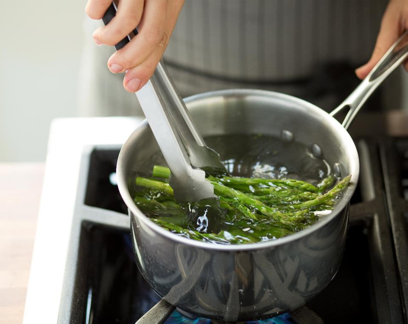 step 10 Place the asparagus in the boiling water and cook for about 4 minutes. The spears should bend slightly when picked up out of the water.