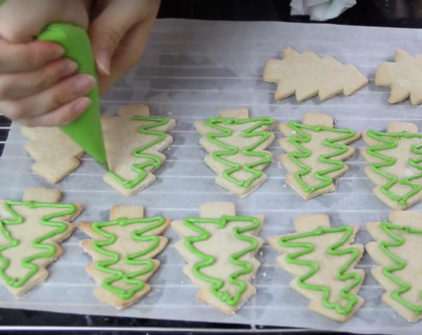 step 16 Transfer your royal icing into a piping bag individually. Pipe an outer layer of green icing for each Christmas tree. This is called outlining.