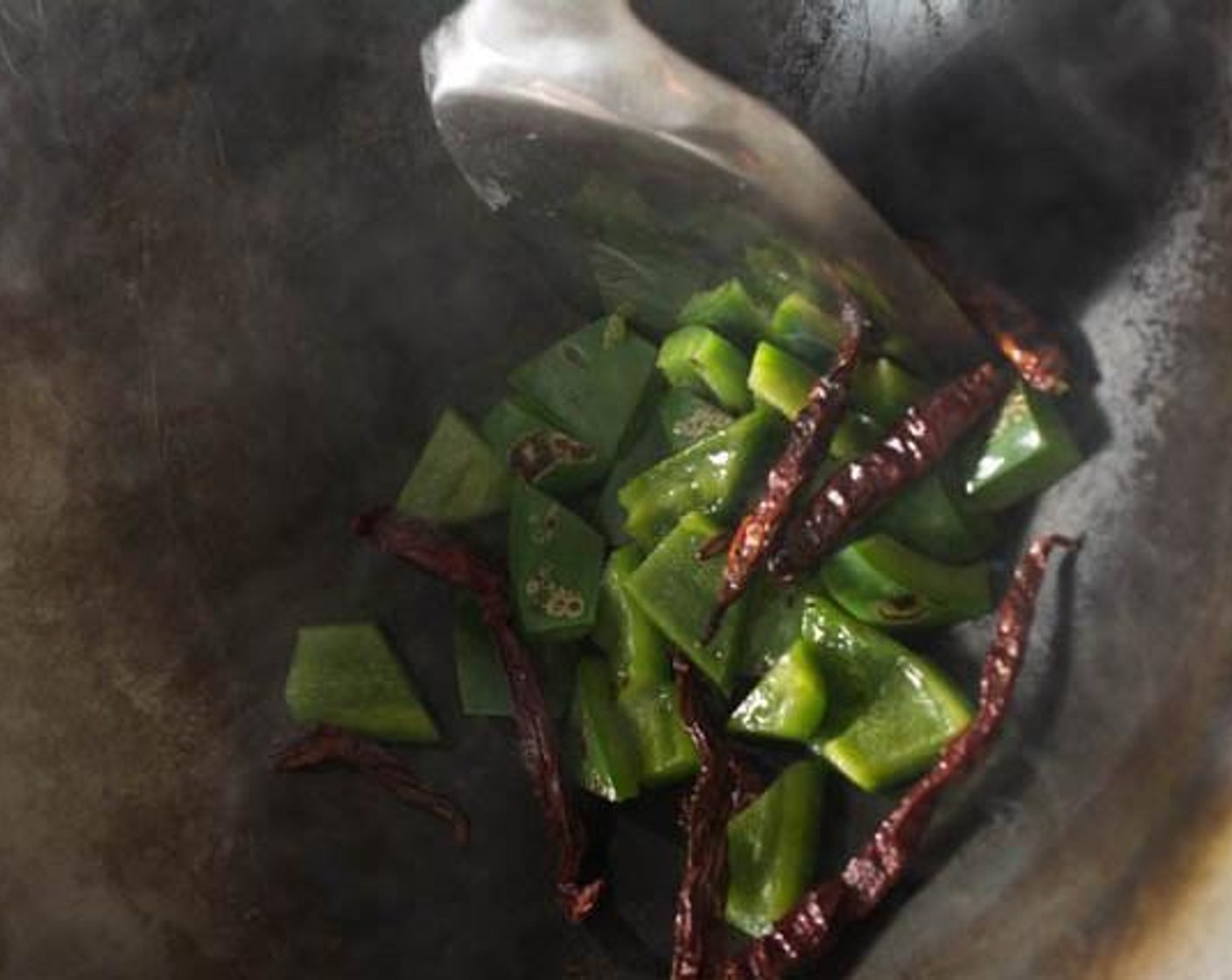 step 2 In a wok over medium heat, heat the Peanut Oil (2 Tbsp). Add the Dried Chili Peppers (8) and Green Bell Pepper (1) and stir-fry slowly, allowing the skin of the bell pepper to blister.