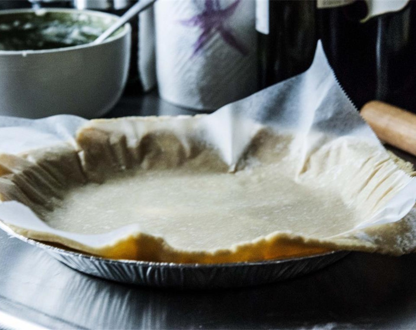 step 9 Heavily grease a pie pan with some butter, then lightly dust it with flour. Lay the dough in the pan, cover with some Baking Powder (1/2 tsp) parchment paper, and beans, and bake at 350 degrees F (180 degrees C) for about 20 minutes.