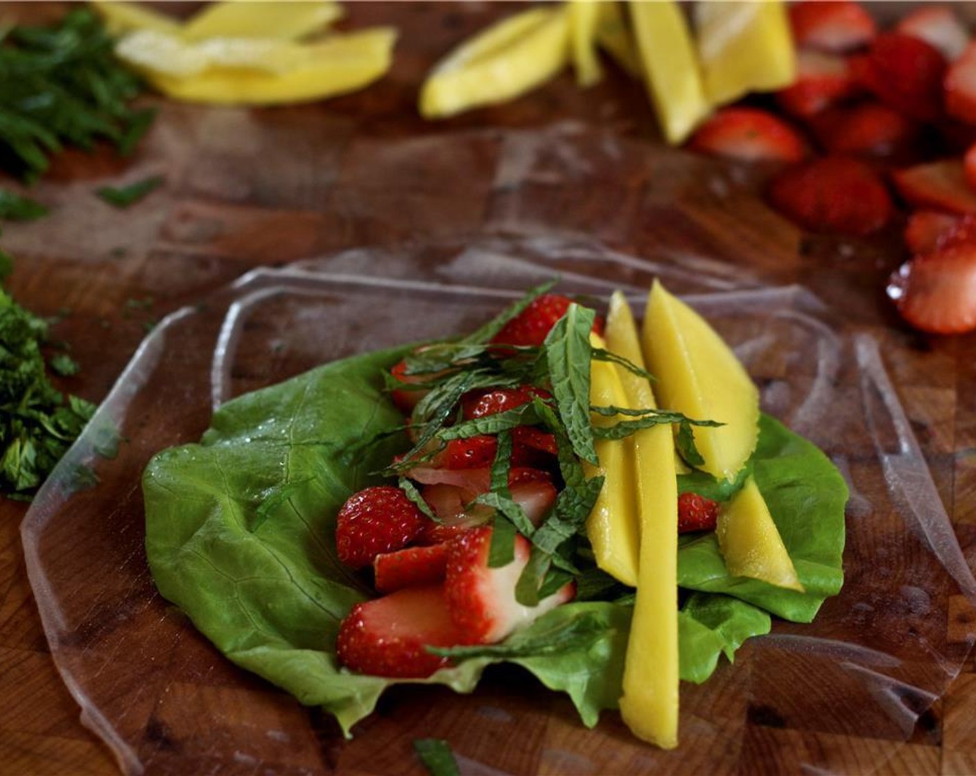 step 4 Lay one piece of the Boston Lettuce (8 pieces) on rice paper wrapper; layer one-eighth each of the strawberries, mango, and sliced fresh mint leaves.