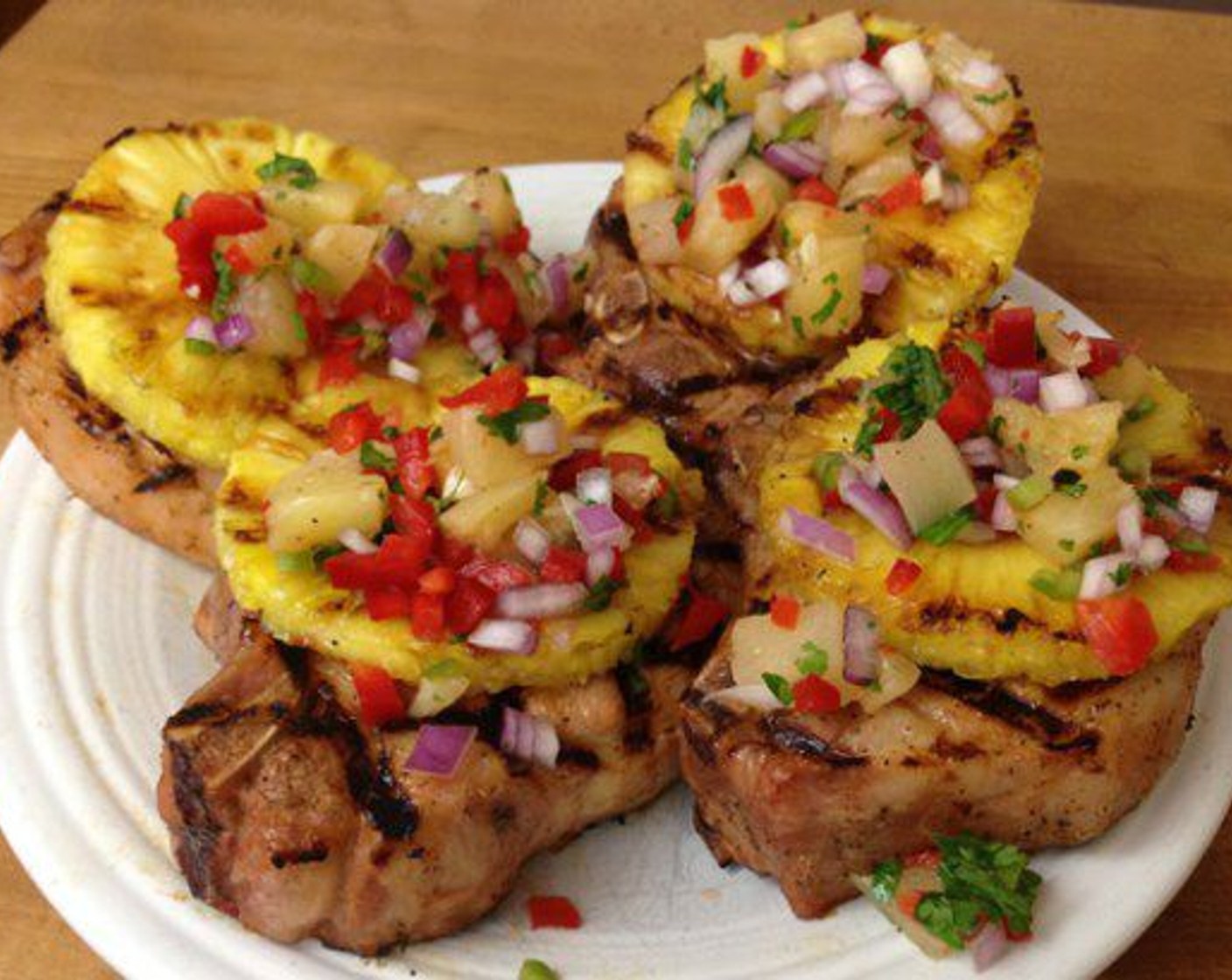 step 8 Once the pineapple is grilled you’re ready to eat. Top each chop with a pineapple ring and garnish with a big spoon of the salsa.