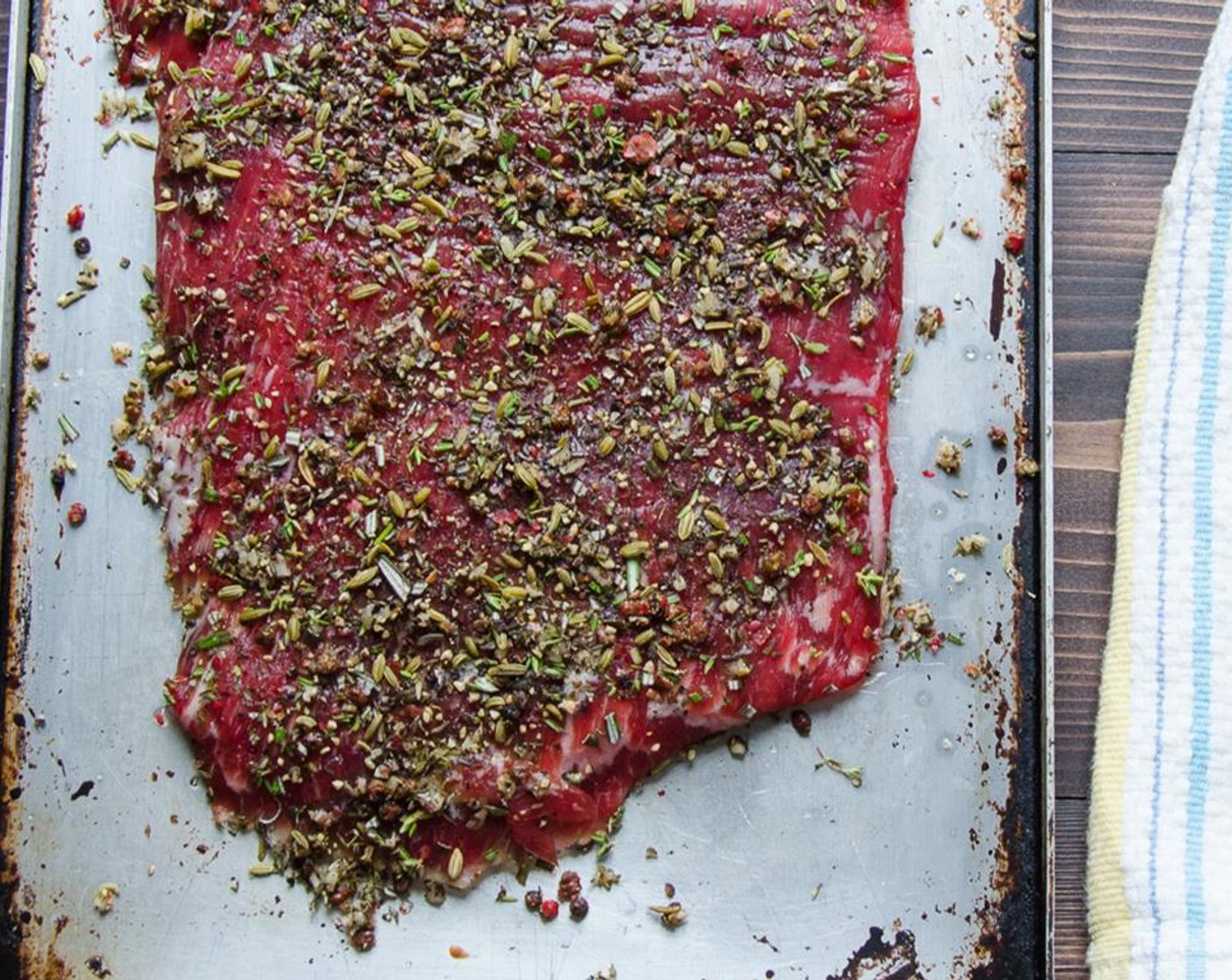 step 5 Sprinkle on half of the peppercorn-herb mixture and press into the steak to adhere. Flip the steak and continue with the remaining olive oil and rub. Press the rub into the steak with your fingers.