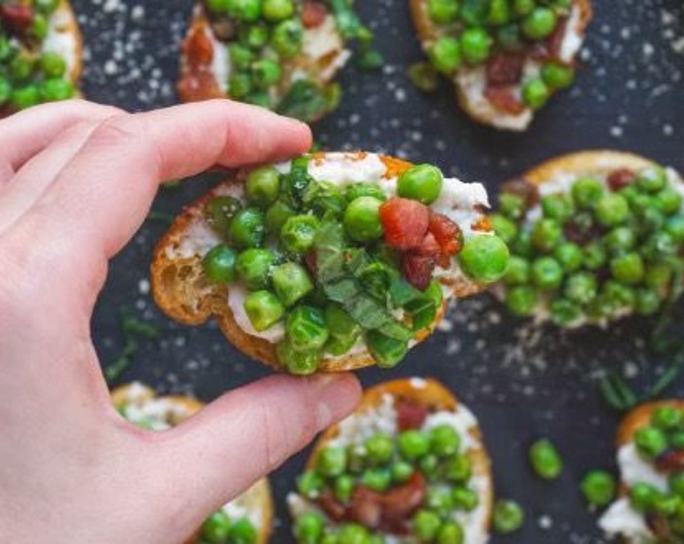 step 12 To assemble, add the pea mixture atop each crostini. The ricotta will act like glue, however you can smash the peas to have it stick better. Repeat until finished.