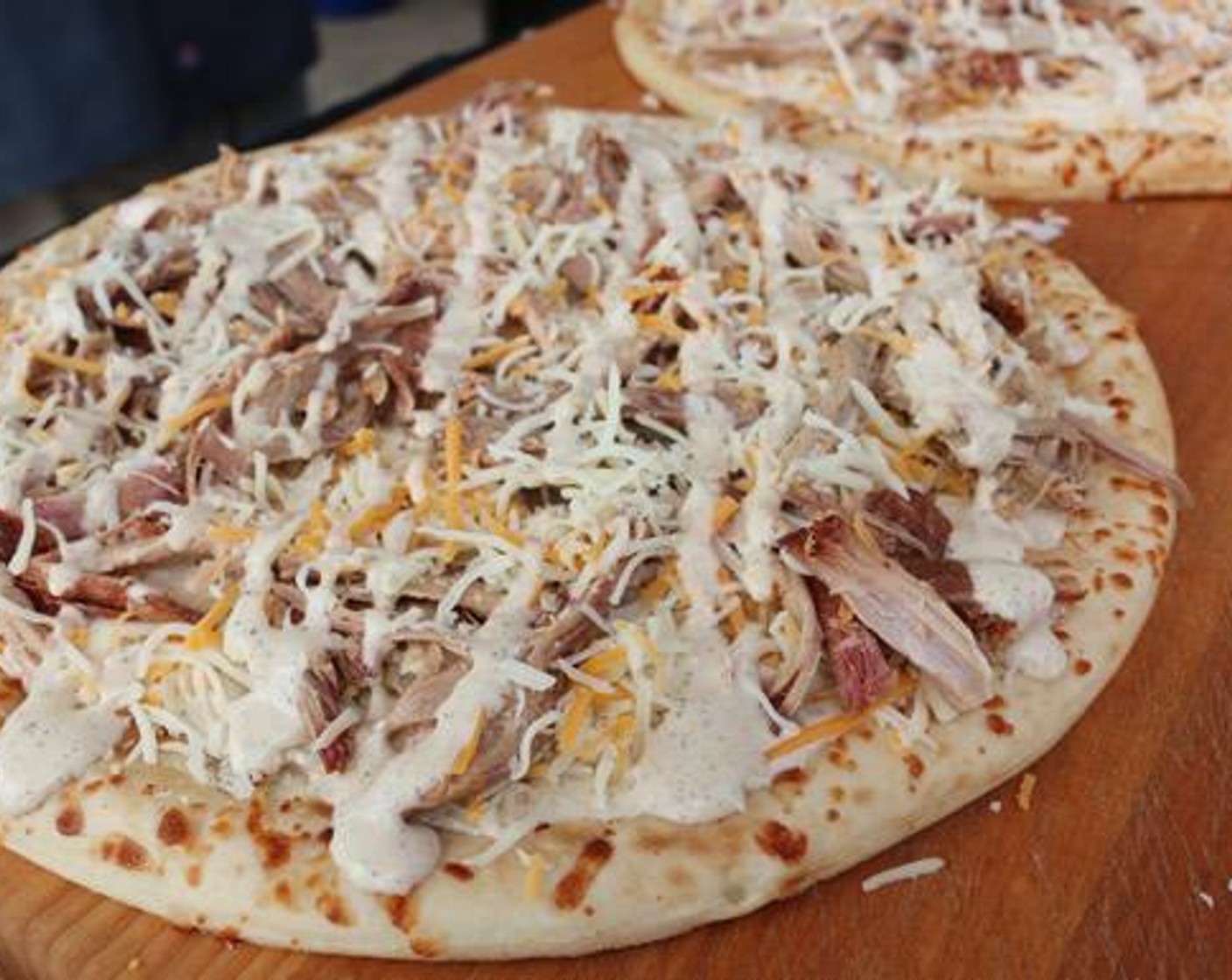 step 4 Top each crust with diced Onion (1), cheese blend, Pulled Pork (1 lb), more cheese, and a light drizzle of the white sauce.