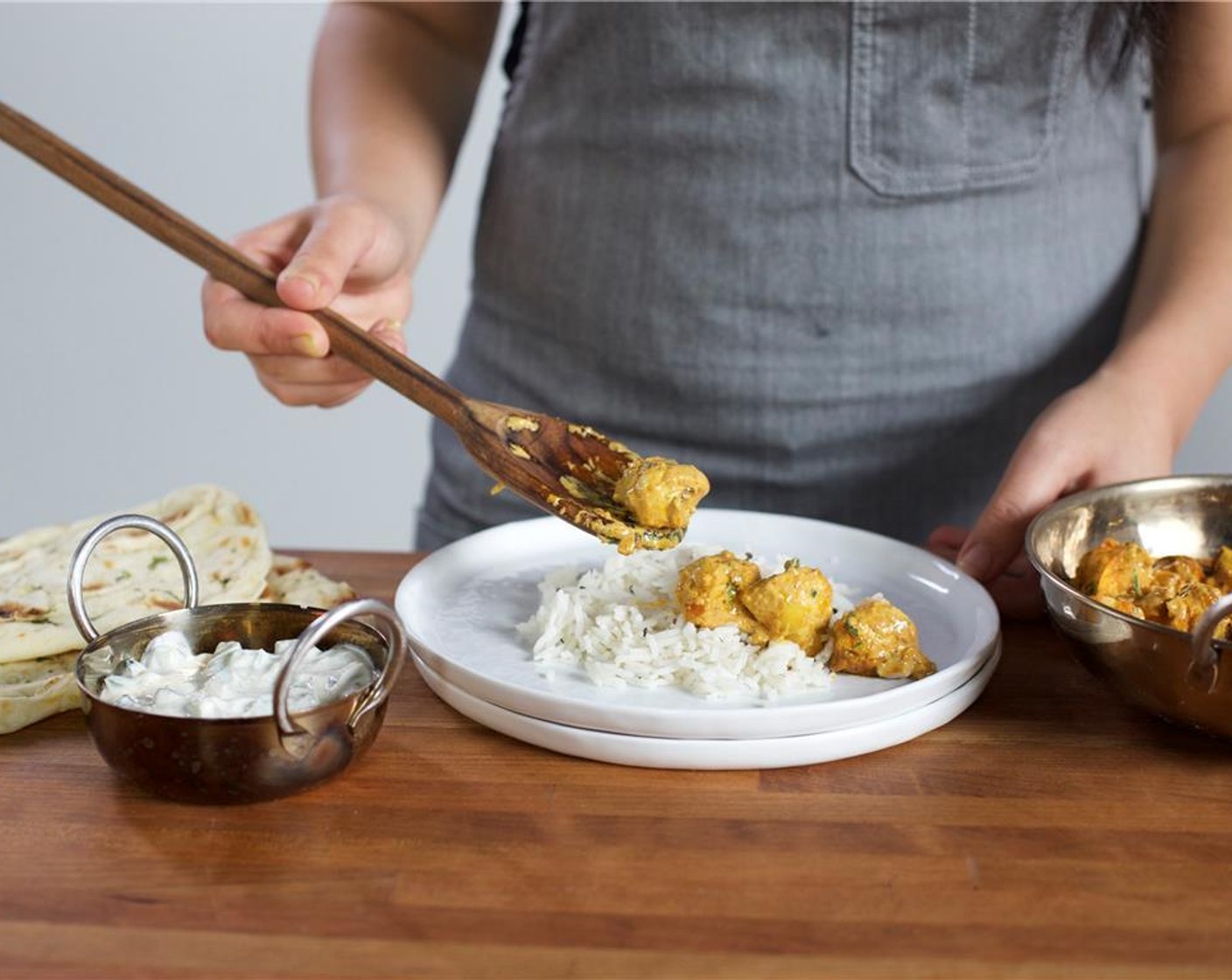 step 22 Divide the rice evenly between two plates. Spoon the chicken with sauce alongside the rice. Garnish with remaining cilantro. Serve with raita and Naan bread on the side. Enjoy!