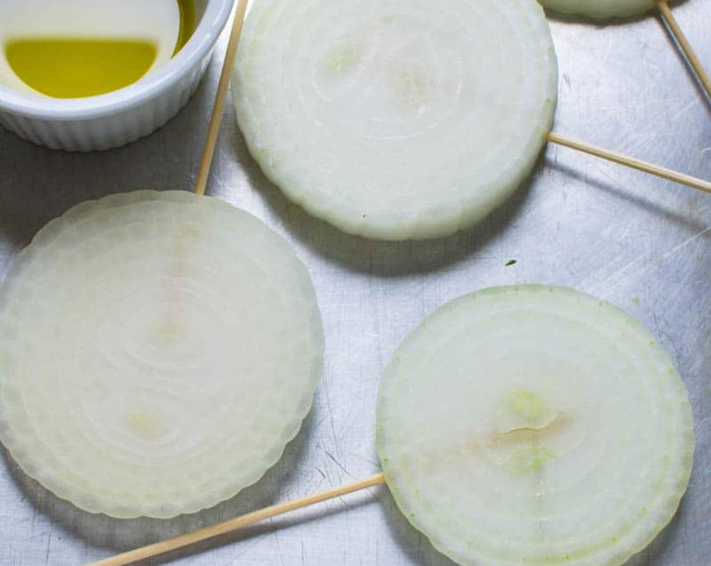 step 2 Depress a 4-inch wooden skewer into the side of the sliced Vidalia Onion (1) so that it pierces all the interior rings and holds them together like a lollipop (that's so the onion doesn't fall apart and slip through the grill grates.)