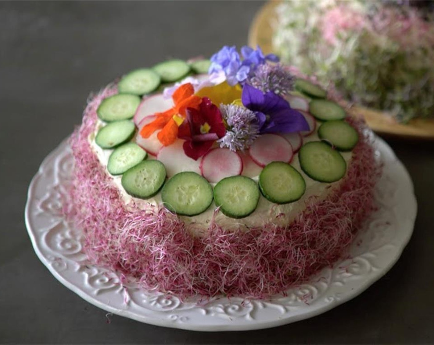 step 10 Add the last layer of the bread onto the cake and press down firmly. Coat the outside of the cake with enough Cream Cheese (to taste) to cover the entire cake. Garnish with Cucumbers (to taste), Edible Flowers (to taste) and Multi-Colored Sprouts (to taste). Serve the Egg Salad Cake and enjoy!