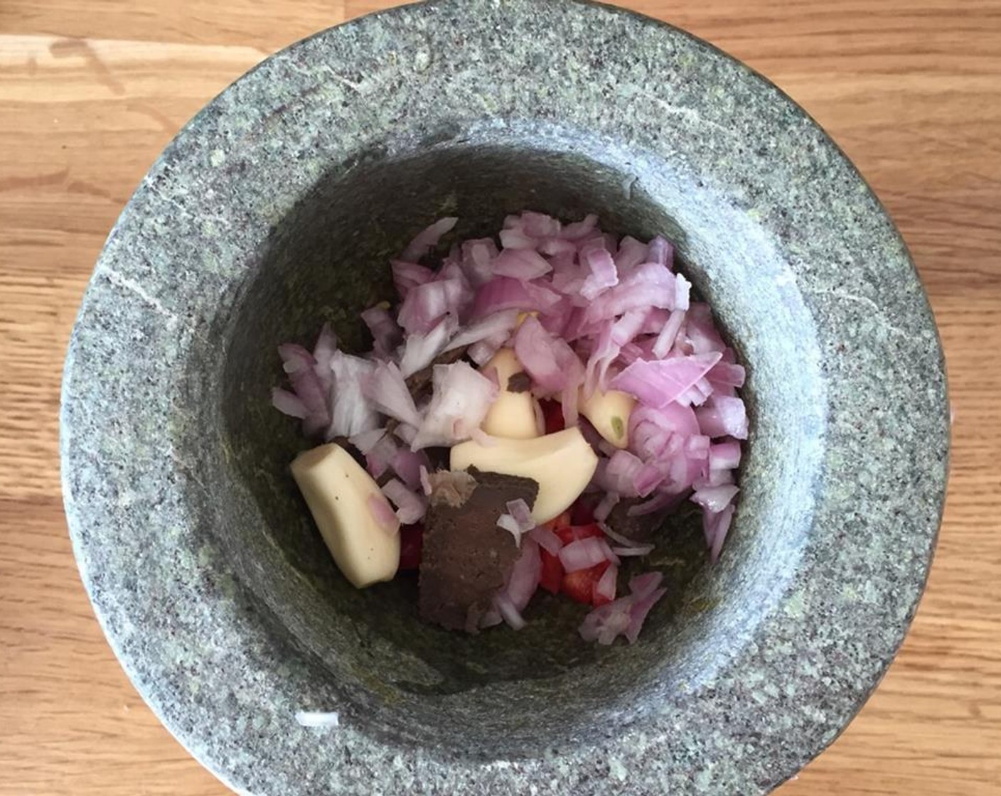 step 2 To make the sauce, add the Shallot (1), Garlic (4 cloves), Red Bird's Eye Chili Pepper (3), Shrimp Paste (1 Tbsp) into a mortar and blend them.