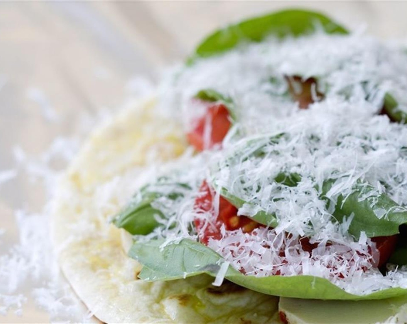 step 3 Add a few slices of the Roma Tomatoes (2) to each flatbread. Sprinkle equal amounts of Mozzarella Cheese (1 cup) on each, and place the Fresh Basil Leaf (1 bunch) over the cheese. Finally, sprinkle with Grated Parmesan Cheese (1/3 cup) over each.
