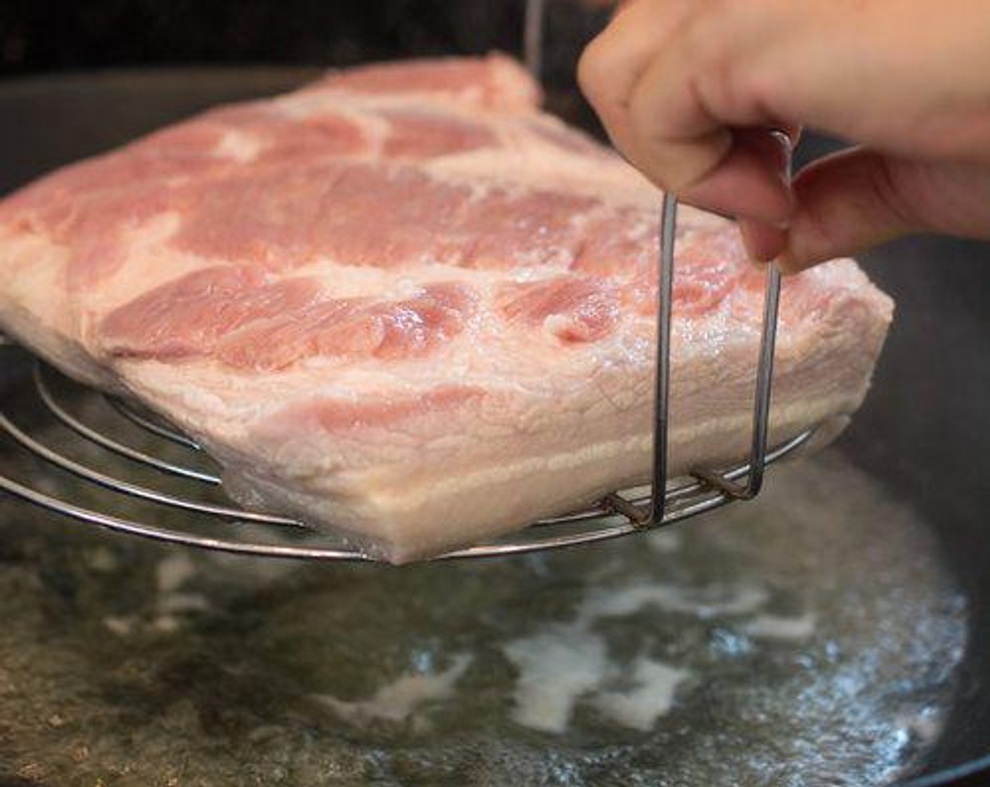 step 2 Place the pork belly, skin side down, into the water, then remove after about 10 seconds.