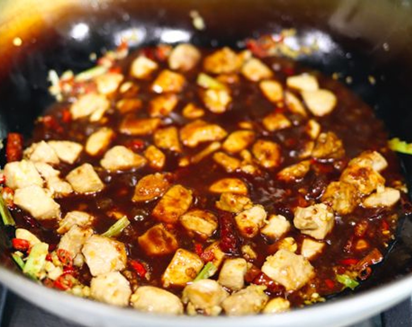 step 13 Give the bowl of sauce a stir to loosen up the corn starch with a spoon, then pour the sauce in a circular motion to cover as many of the chicken pieces as possible. Stir-fry and toss continuously to coat all the chicken pieces with the sauce.