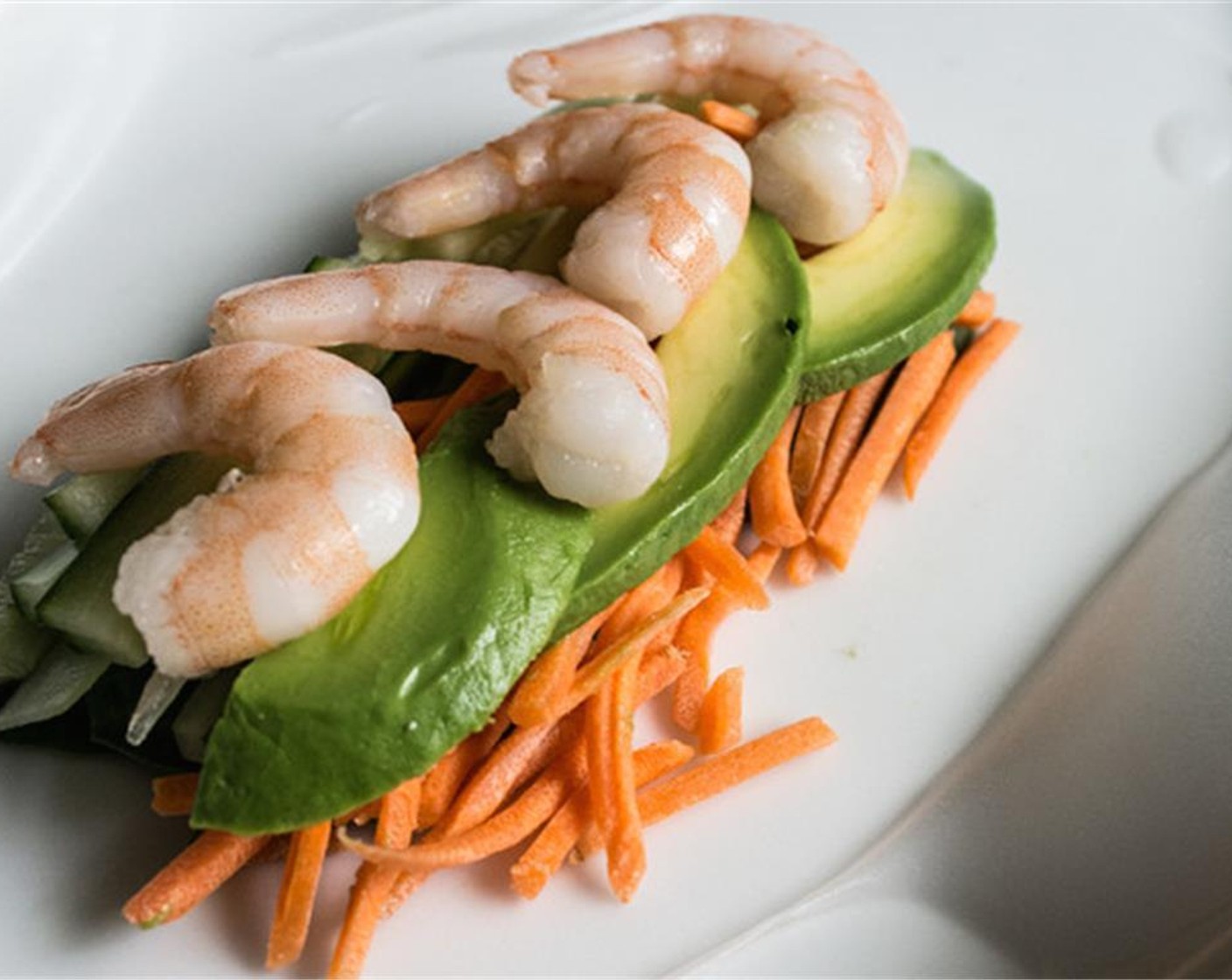 step 2 Gently pat wrapper dry, then arrange vegetables in the center of each wrapper. Start with the Spinach Leaves (2 cups), then top with strips of Cucumber (1) and shreds of Carrot (1 cup), followed by Avocado (1), then topped with Medium-Large Cooked Shrimp (24), four per roll.