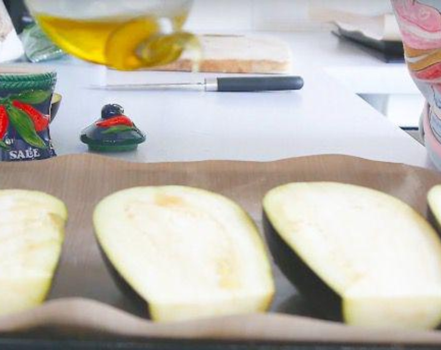 step 2 Cut the Eggplants (4) in half and drizzle some Olive Oil (as needed) and sprinkle a little bit of salt over each half. Place them on a baking tray with the cut face down.