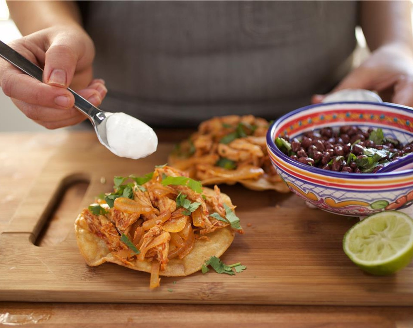 step 19 Divide the tostada shells between two plates. Spread Sour Cream (1/2 cup) over the tostada shells and top each shell with chicken tinga mixture and remaining cilantro. Place the black beans in a small bowl on the side.
