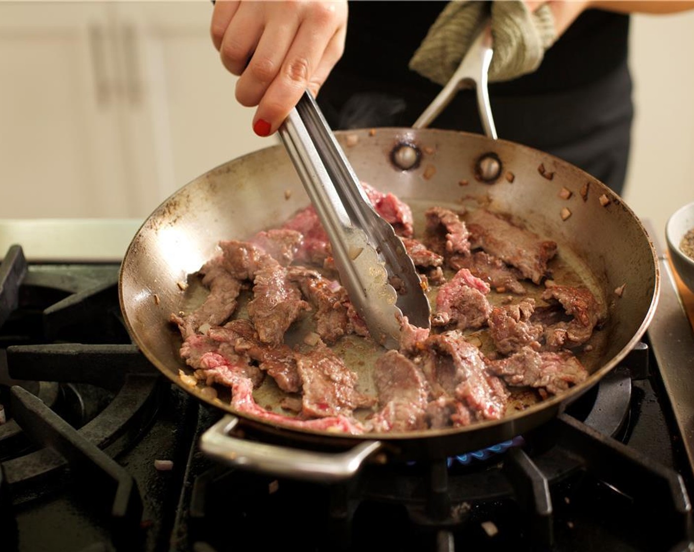 step 8 Heat the same large saute pan you used for the vegetables over medium high heat. Add 1 tablespoon of olive oil and whe hot, add the flank steak in a single layer and sear until browned, 2 minutes. Flip the steak over and cook for 1 more minute.