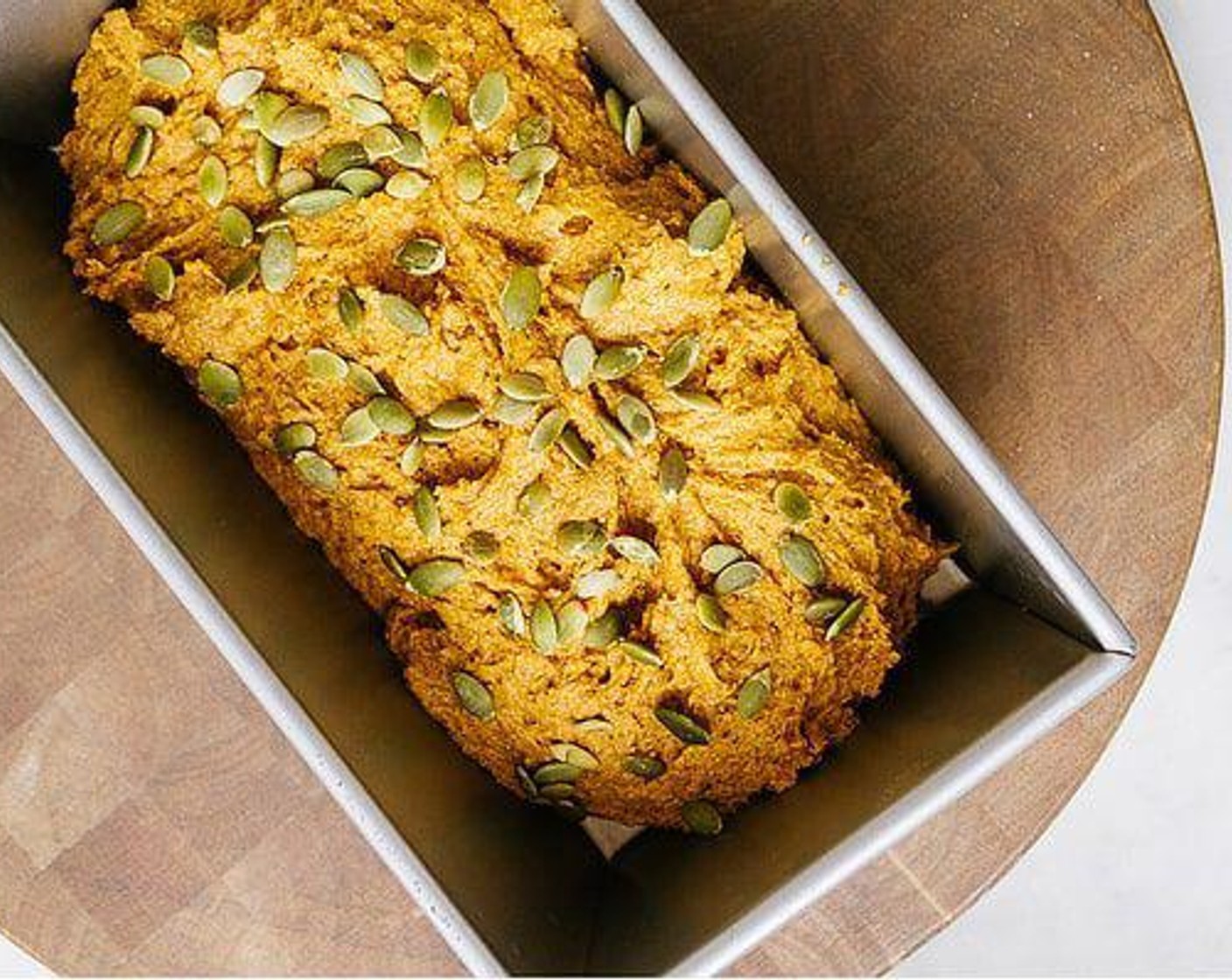 step 5 Pour batter into a lightly greased loaf pan. Sprinkle the top with Pepitas (to taste), if desired. Bake for 50-55 minutes.