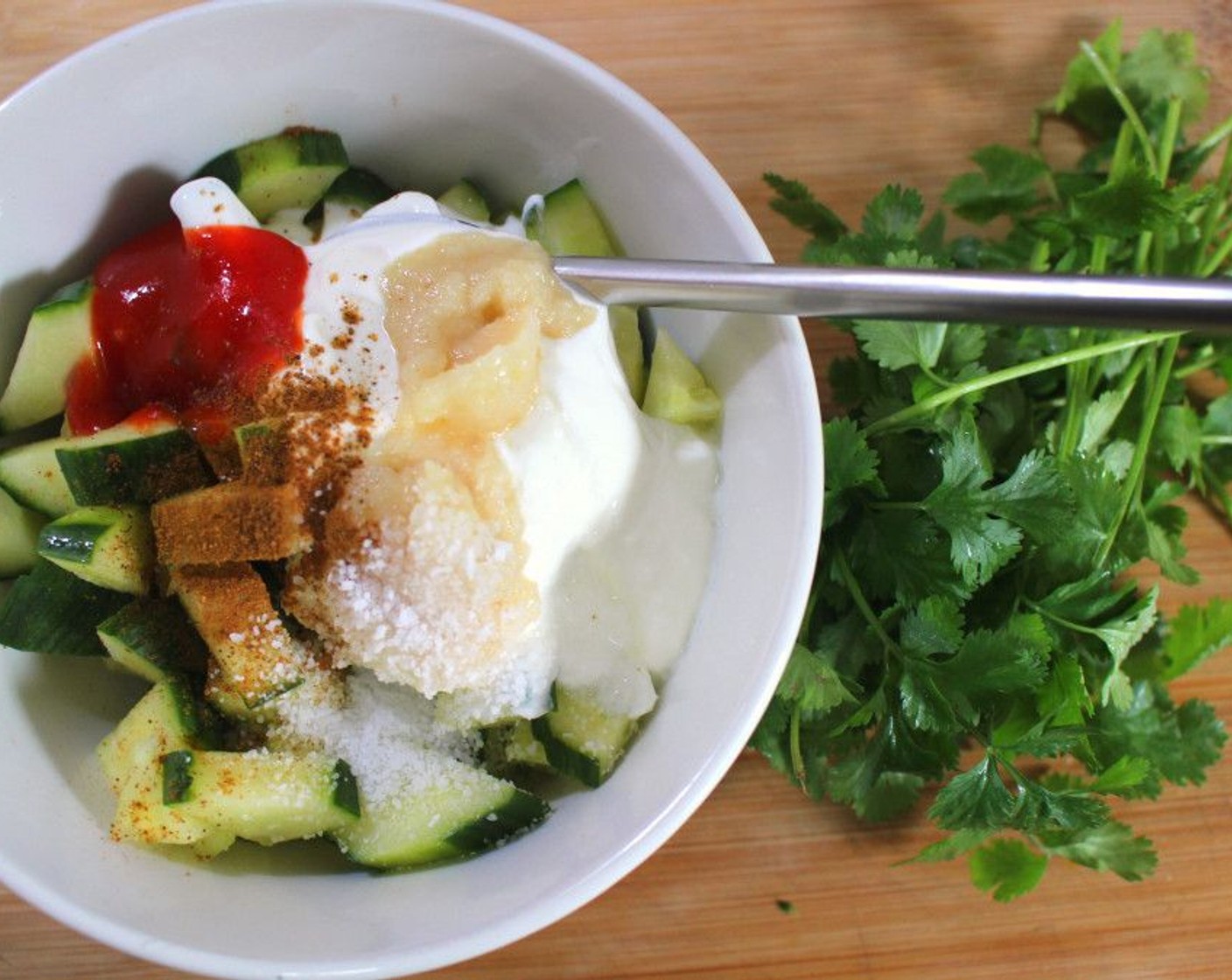 step 7 In a bowl combine Cucumber (1), Fresh Cilantro (2 Tbsp), Garlic Paste (1 Tbsp), Greek Yogurt (1/3 cup), Chili Sauce (1 tsp), Garam Masala (1 pinch), Lime (1), and Kosher Salt (to taste) to make the cucumber salad.