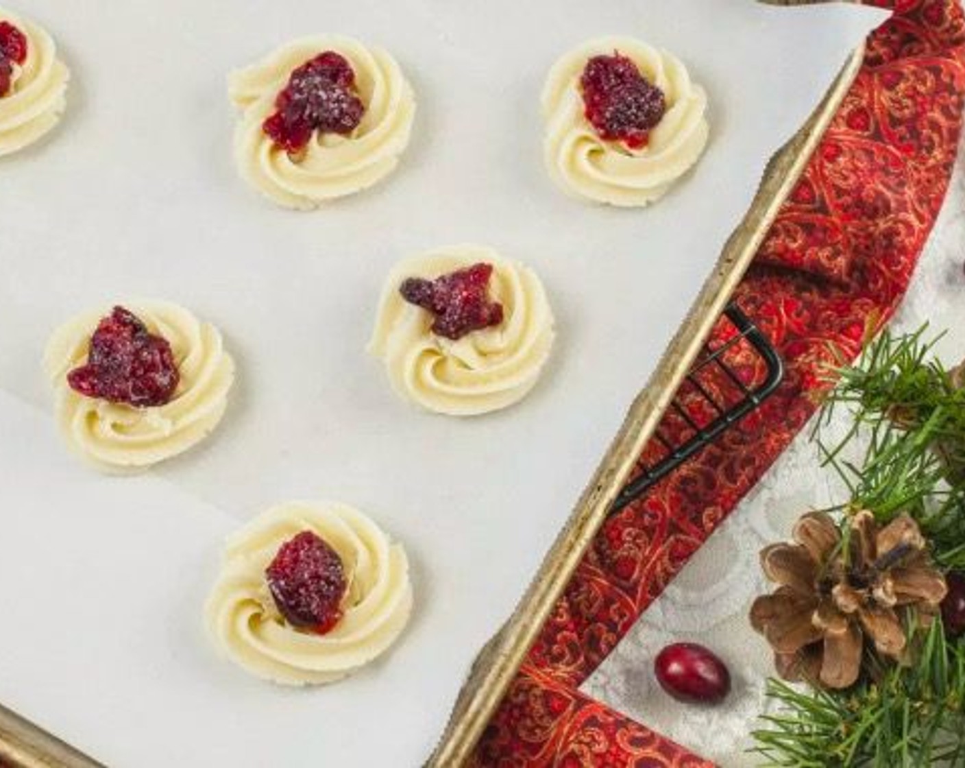 step 7 Scoop dough into a large pastry bag fitted with a 1M tip. Line large baking sheets with parchment and pipe dough into approximate 1 3/4-inch to 2-inch rosettes with 2-inch spacing. Press an approximate 1/2 teaspoon of roasted cranberries into the center of each cookie. Top centers of cookies with course sugar.