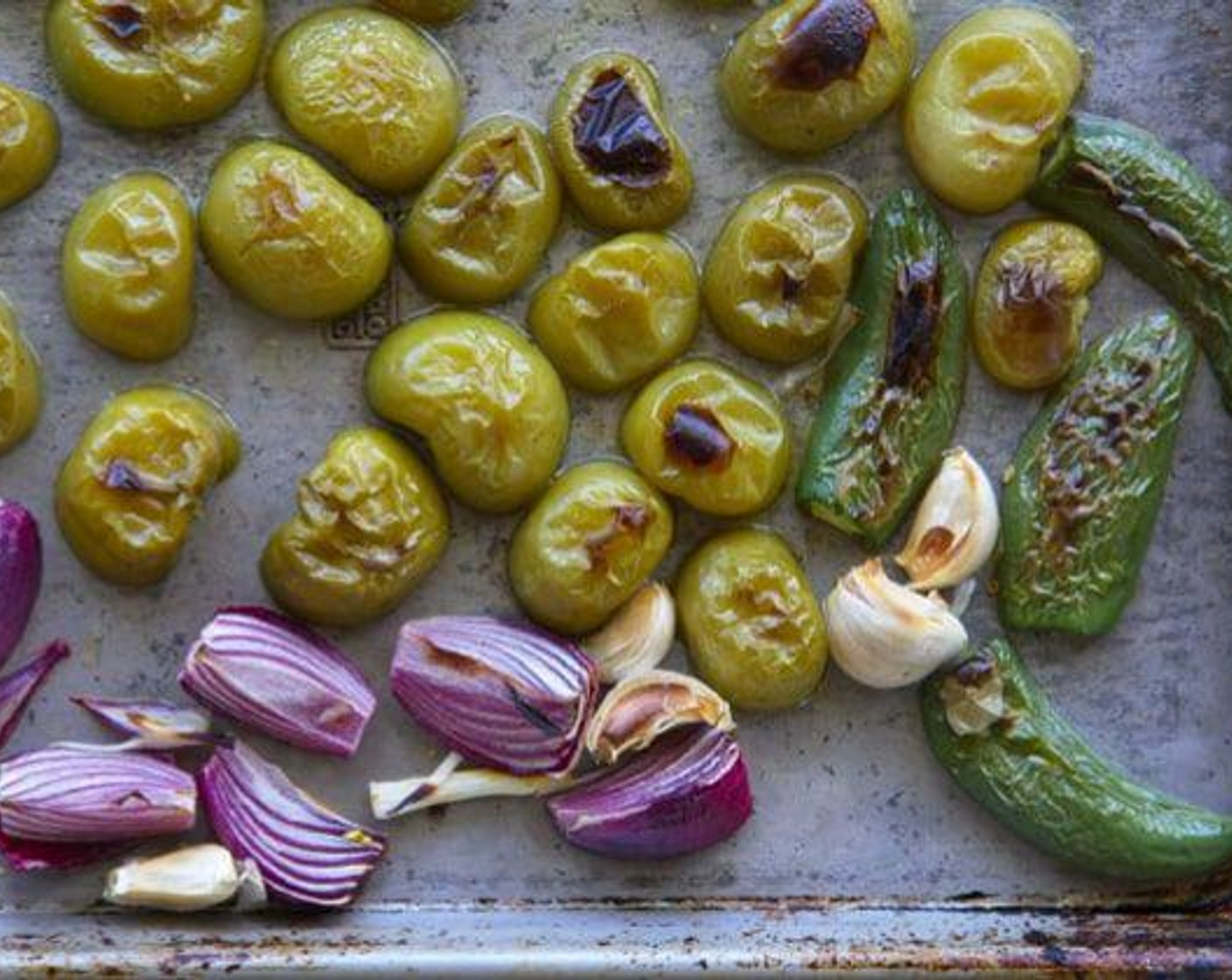 step 1 Add your Tomatillos (1.5 lb), Jalapeño Peppers (2), Yellow Onion (1), and Garlic (1/2 bulb) to a sheet pan. Lightly drizzle oil and sprinkle with Salt (to taste) and Ground Black Pepper (to taste).