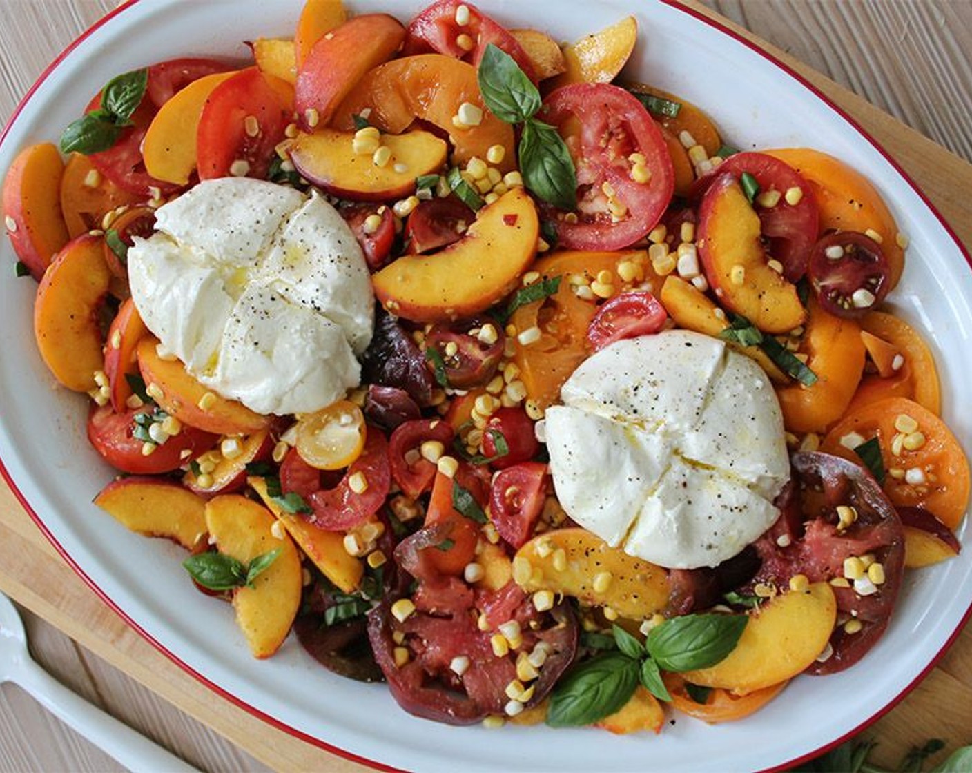 step 3 Spread the tomatoes, peaches, and corn in an even layer on a large serving platter. Place the balls of Burrata Cheese (2 pieces) on top and using a paring knife, carefully cut an ‘X’ into the top of each ball to cut it into quarters. Sprinkle the salad with Fresh Basil (to taste) and Sea Salt Flakes (to taste), drizzle with the remaining dressing, and serve.