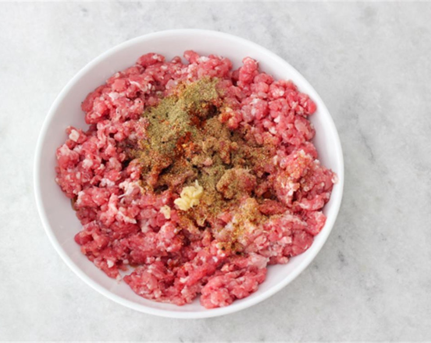 step 1 Add the Salt (1/2 Tbsp), Ground Black Pepper (to taste), Garlic (1 clove), Dry Mixed Spice (1 tsp), and Maple Syrup (1 Tbsp), Paprika (1/2 tsp), Ground Coriander (1/2 tsp), Crushed Red Pepper Flakes (1/4 tsp) to the Ground Pork (1.5 lb) and mix to combine.