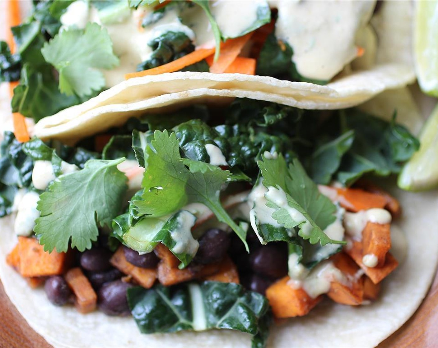 step 9 Put the sweet potato and black beans mixture in first, top with slaw and peanut sauce, and garnish with a few bits of Fresh Cilantro (to taste). Serve with Lime Wedge and enjoy!