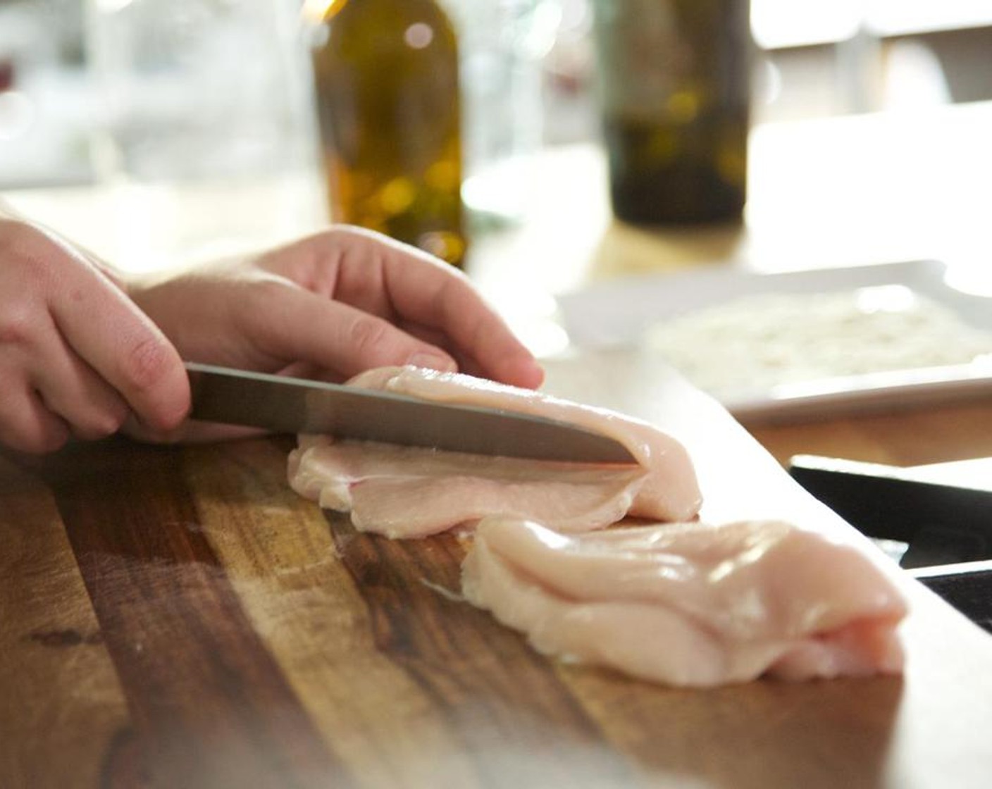 step 6 Place a hand on top of the breast. Hold your knife parallel to the cutting board and slice nearly all the way through, leaving the opposite end connected.