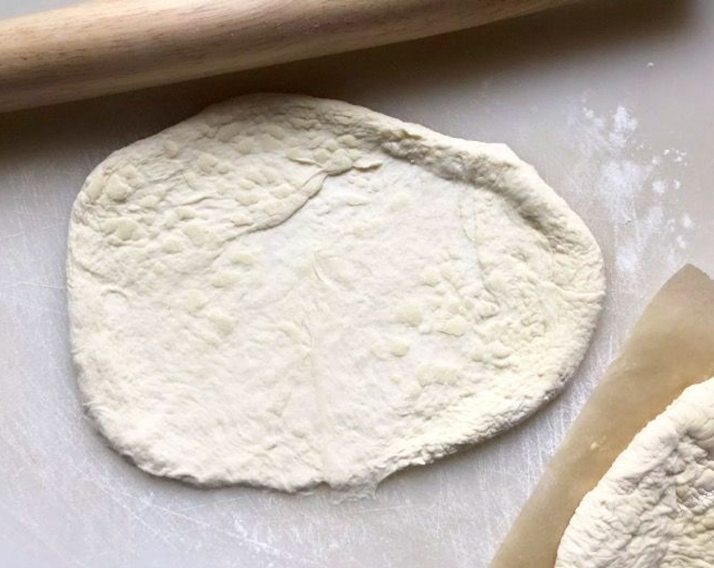 step 3 Punch the Pizza Dough (1 lb) down and divide it into two equal portions. On a surface dusted with All-Purpose Flour (to taste), roll each dough portion into an 8 by 10-inch oval.