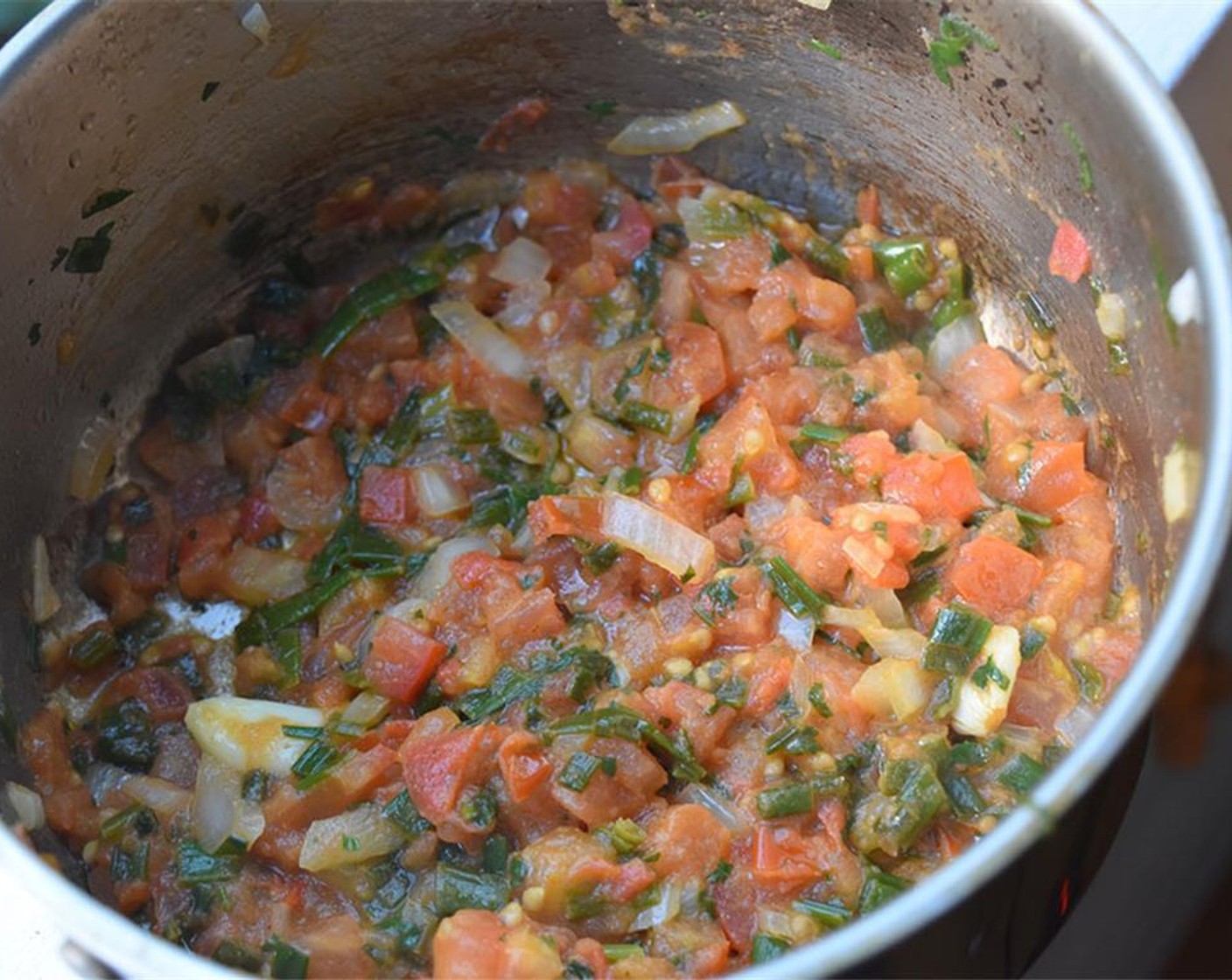 step 3 While beans are cooking, make the guiso. Heat Vegetable Oil (2 Tbsp) in a large skillet. Add Tomatoes (2 cups), Scallion (1), Onion (1 Tbsp), Garlic (2 cloves), Fresh Cilantro (1/2 bunch), and Ground Cumin (1/4 tsp). Cook for 10-15 minutes.