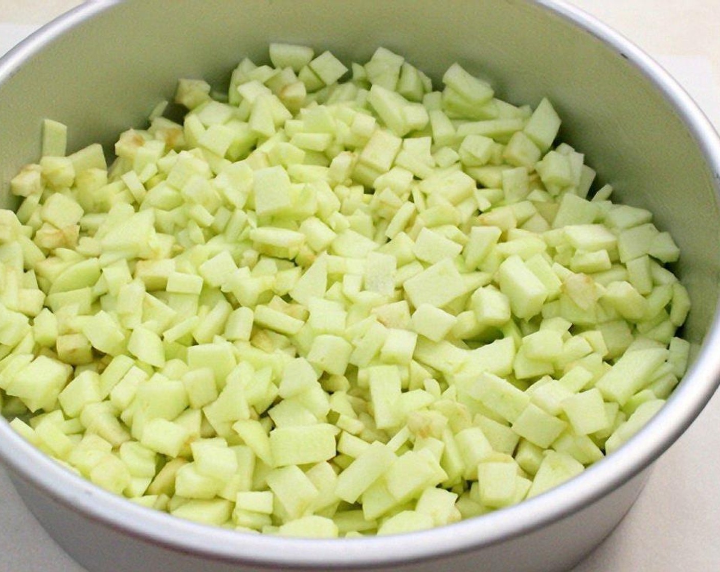 step 6 Meanwhile, peel the Granny Smith Apples (5) and cut into small, thin pieces. Add the apples to the prepared cake pan.