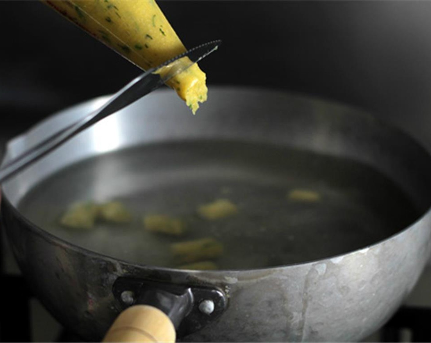 step 11 Keep the water at a very gentle simmer, then squeeze the dough out of the piping-bag while “cutting” it into the water with a small knife. If the dough is sticking to the knife, just dip the knife in the hot water then continue.