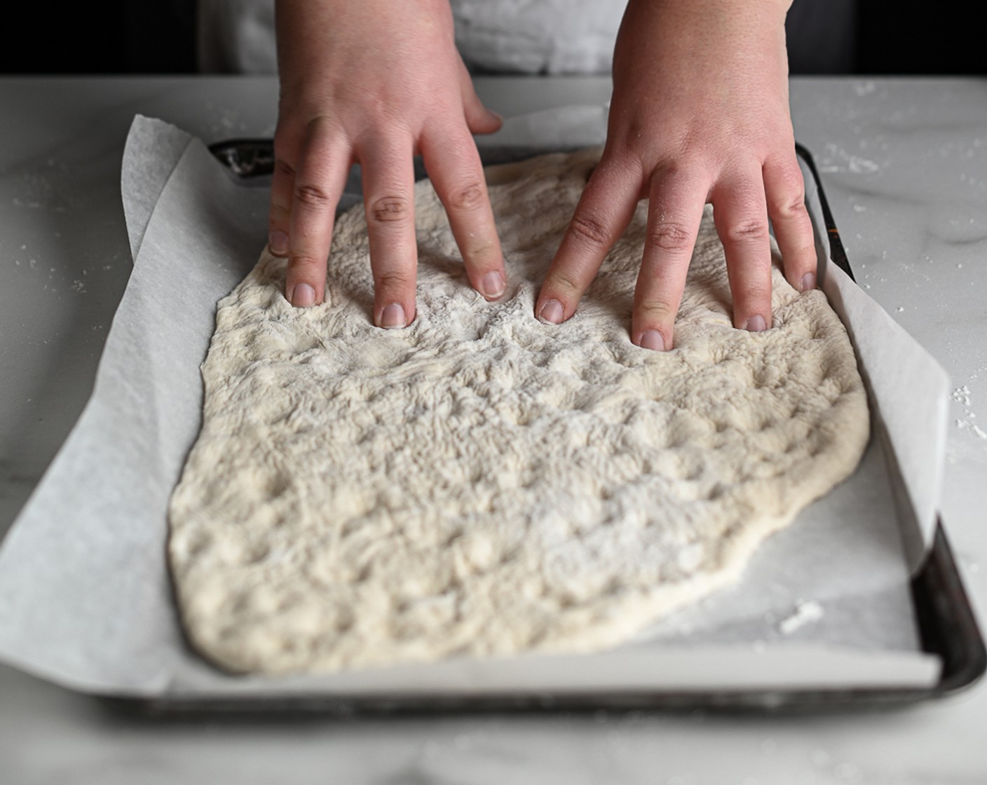 step 6 On a floured surface, knock down the bread dough and use your fingertips to press it into a lined baking sheet.