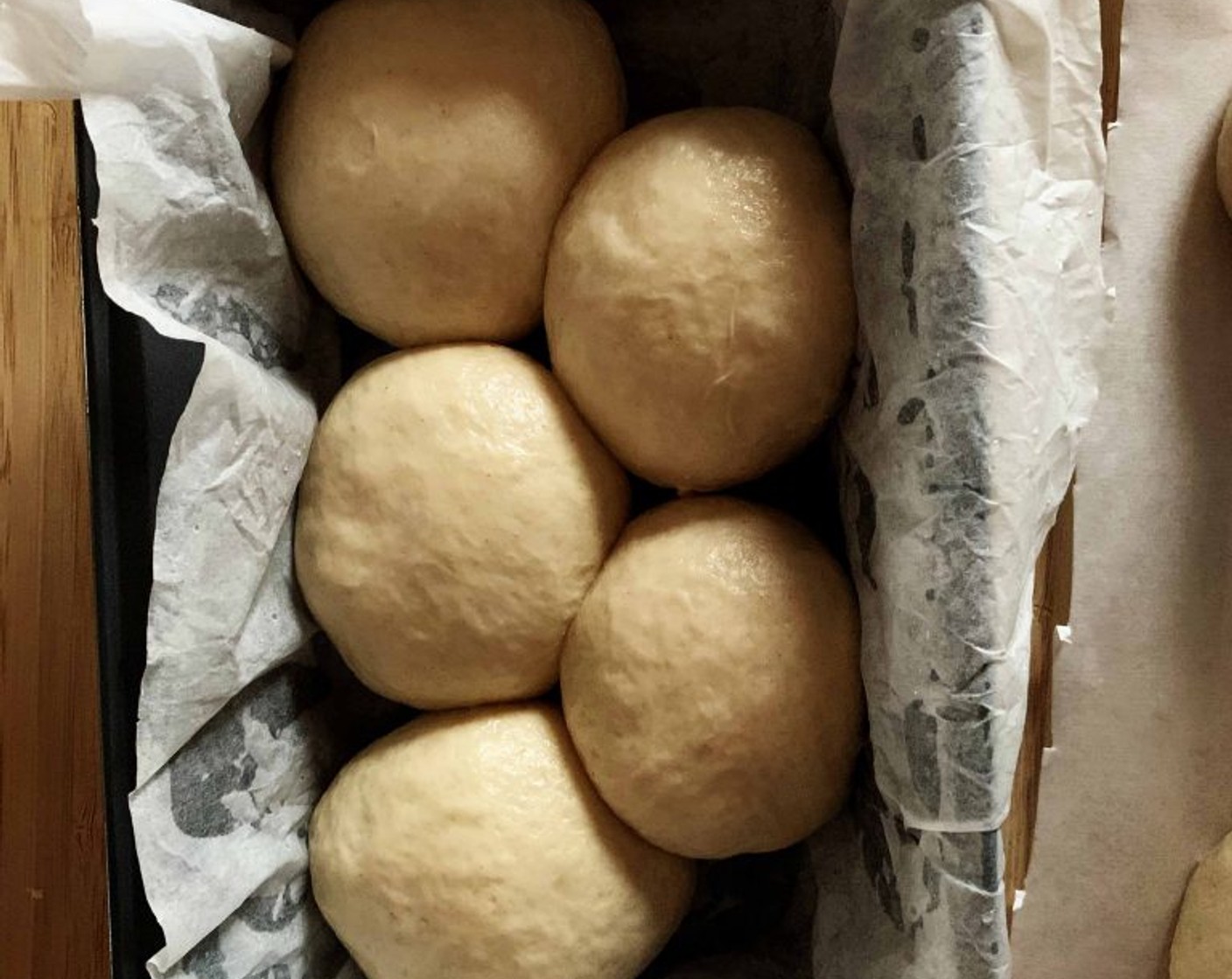 step 8 Line a bread pan with parchment paper, and lay the balls of dough 4 on one side and 3 on the other. Cover with plastic wrap and let it rest until it doubles in size, depending on room temperature this might take from 1 to 2 hours.